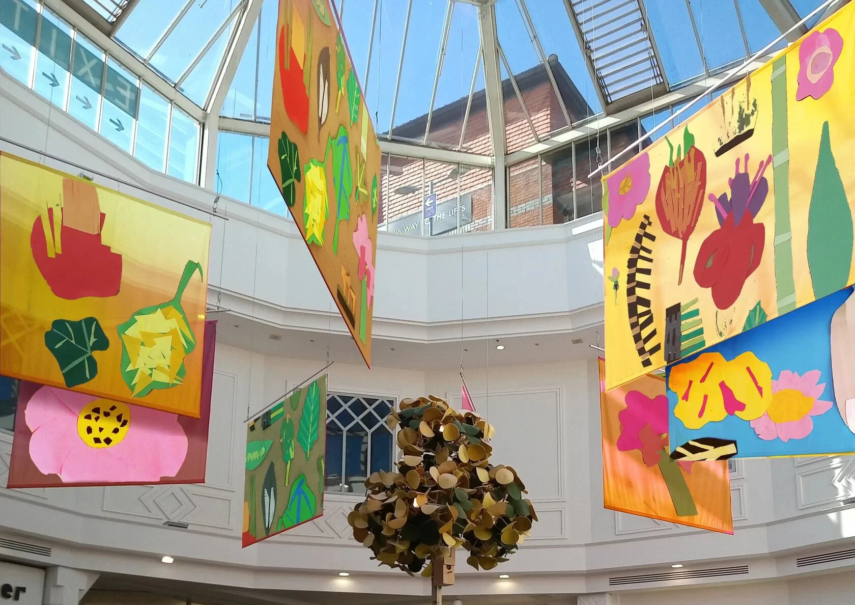 Photo of colourful banners of children's artwork hanging in a sunny exhibition space