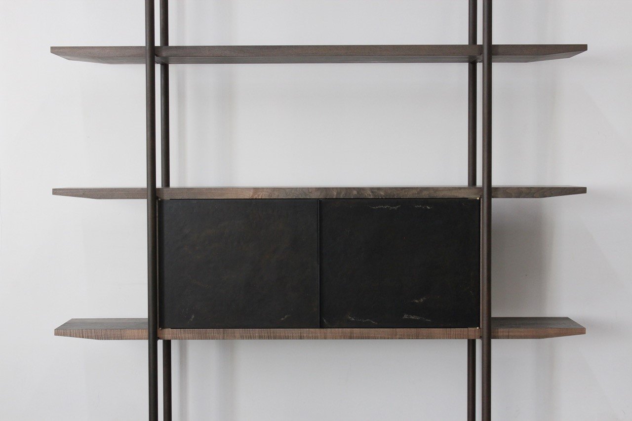 Empty modern shelving unit with black cabinet doors against a plain white wall.