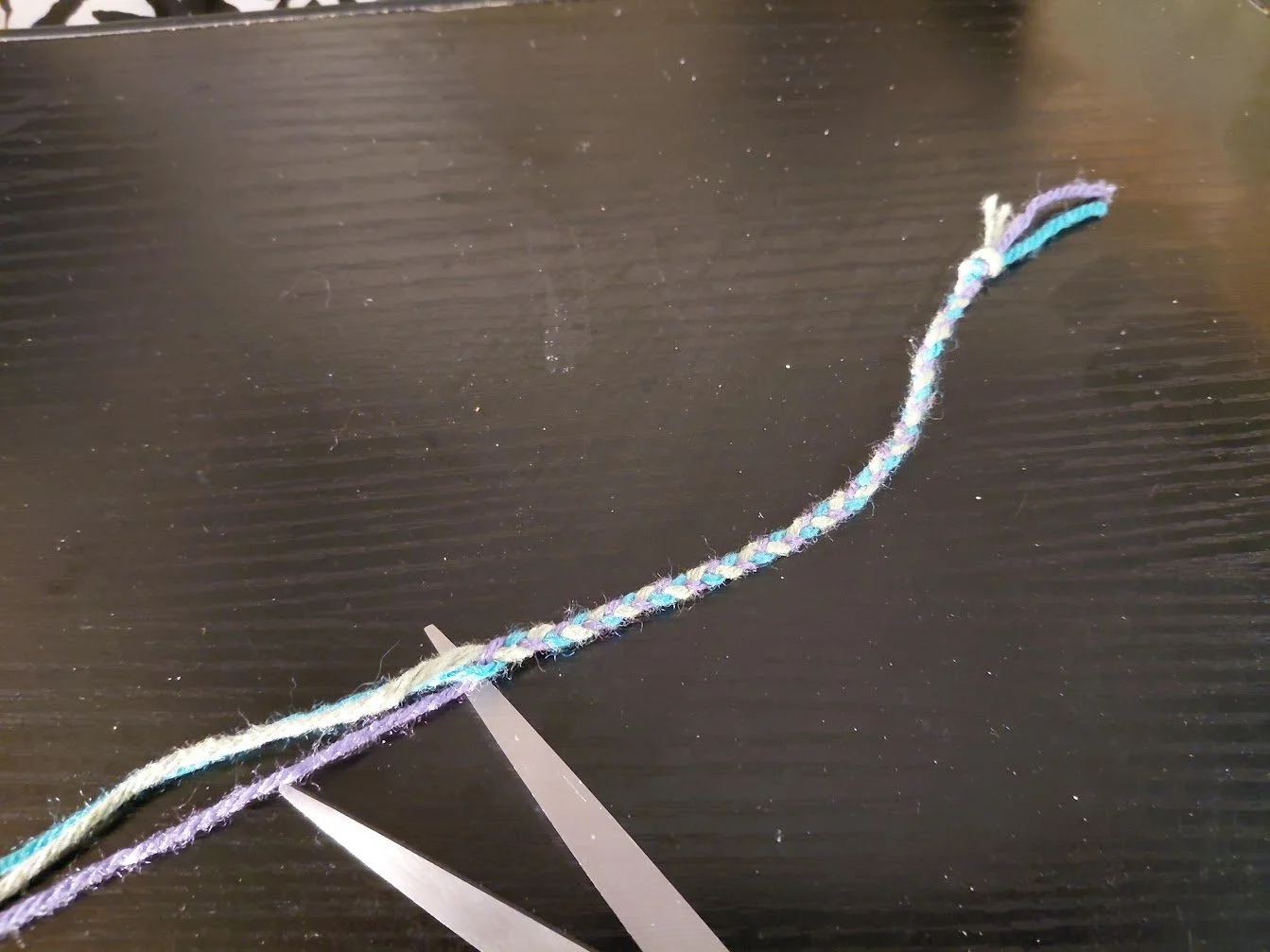 A photo of braided yarn, the braid going for about 5 inches, laid out on a dark surface.