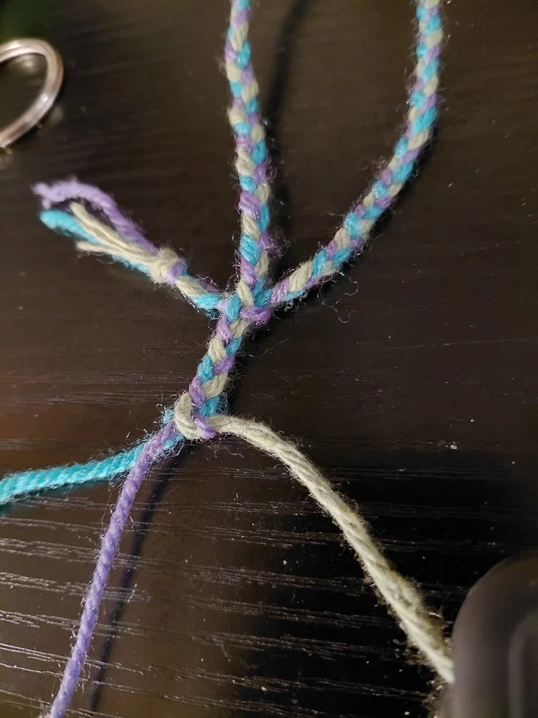 Braided yarn, focus on how the green and purple strands have been knotted via a simple loop knot