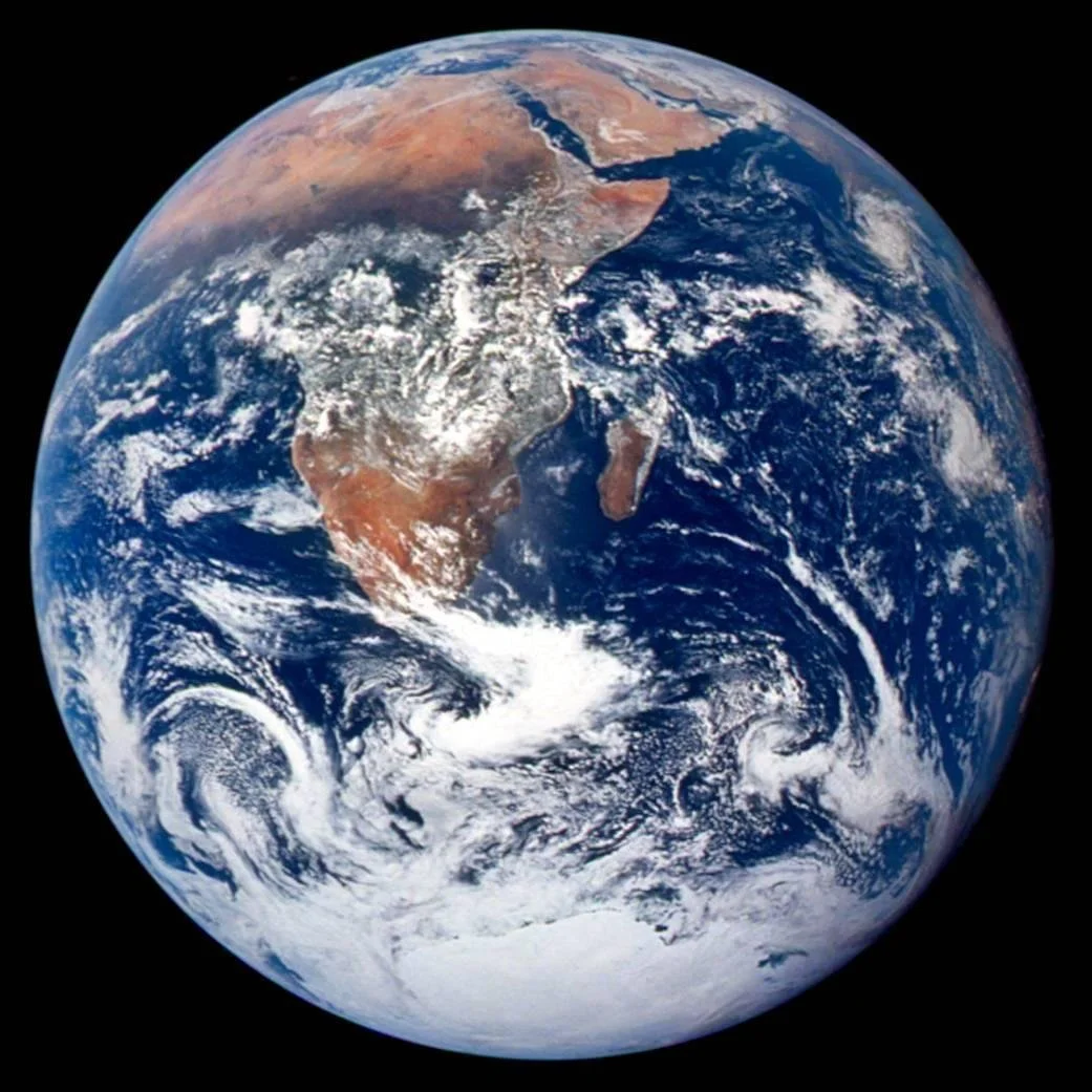 An image of the earth, white swirling with blue and brown, taken from space, rotated so that Antarctica is at the bottom