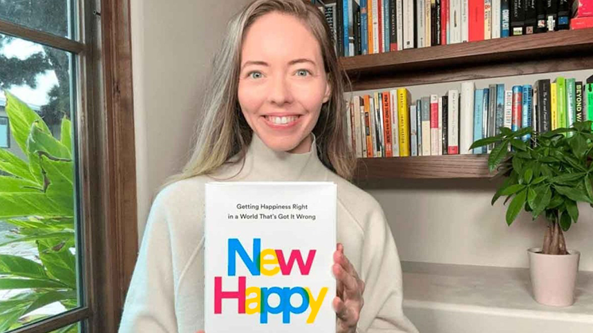 Stephanie Harrison smiling, holding the book New Happy