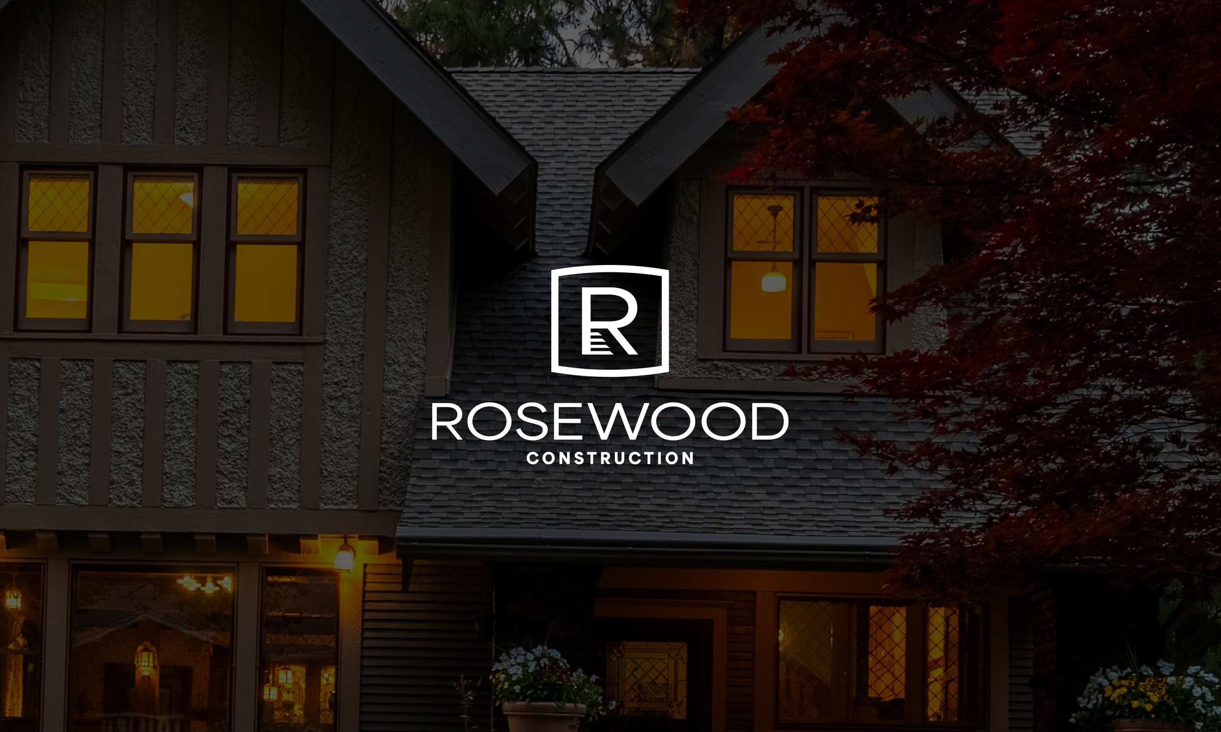 A house with lit windows at dusk, surrounded by trees, with a rosewood construction logo and text overlay.