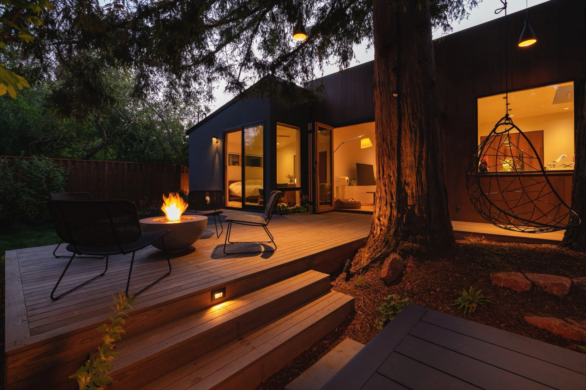Modern home with entertaining area with evening lighting under the Redwood trees