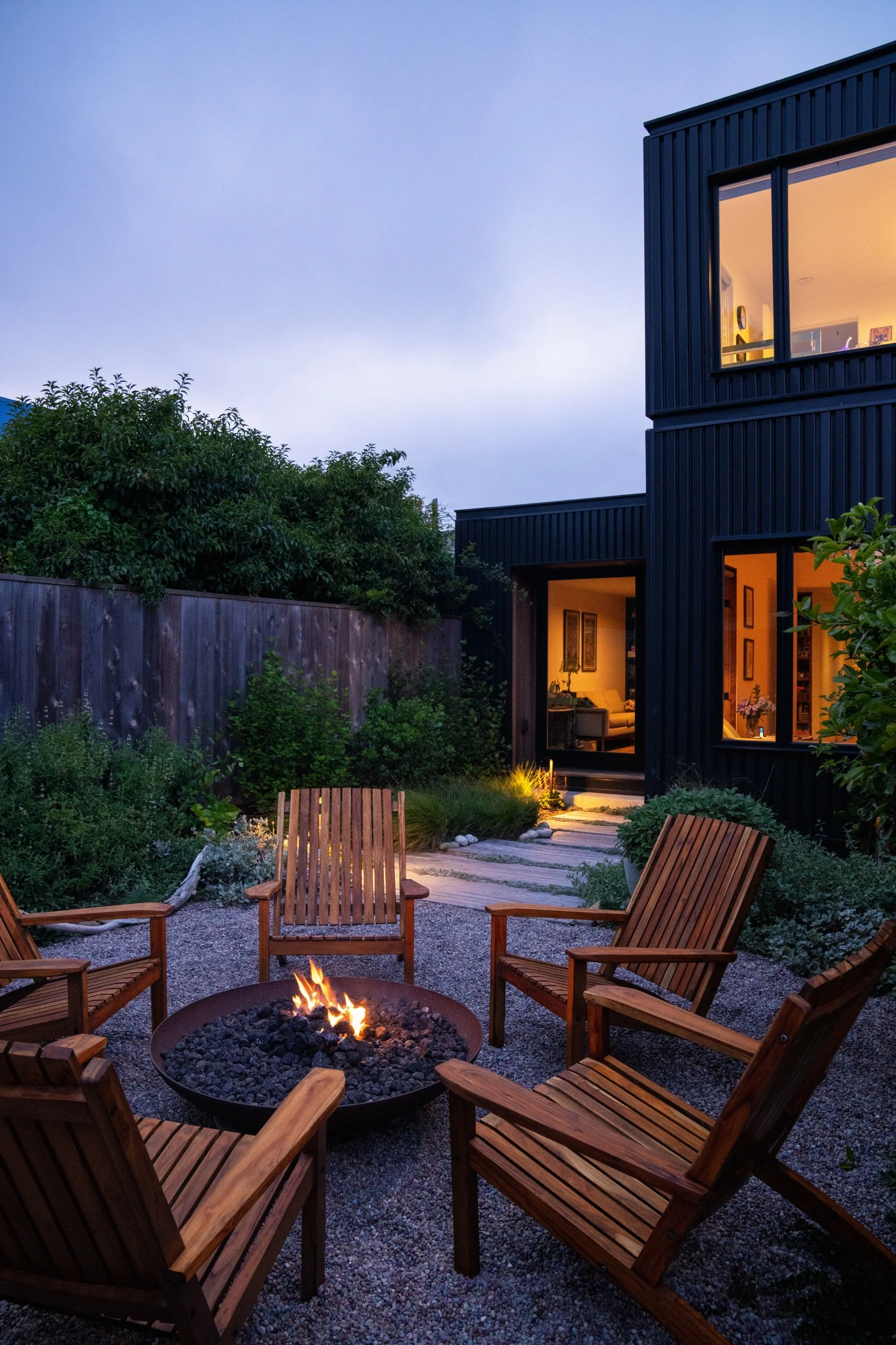 Firepit with seating at dusk in front of a modern home