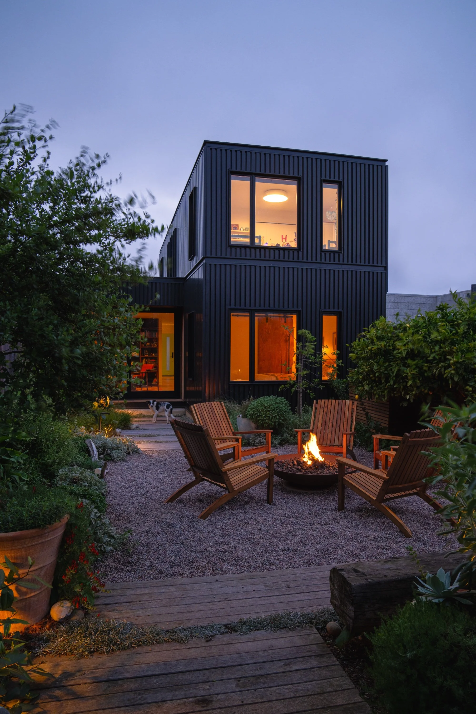 Firepit with seating at dusk in front of a modern home