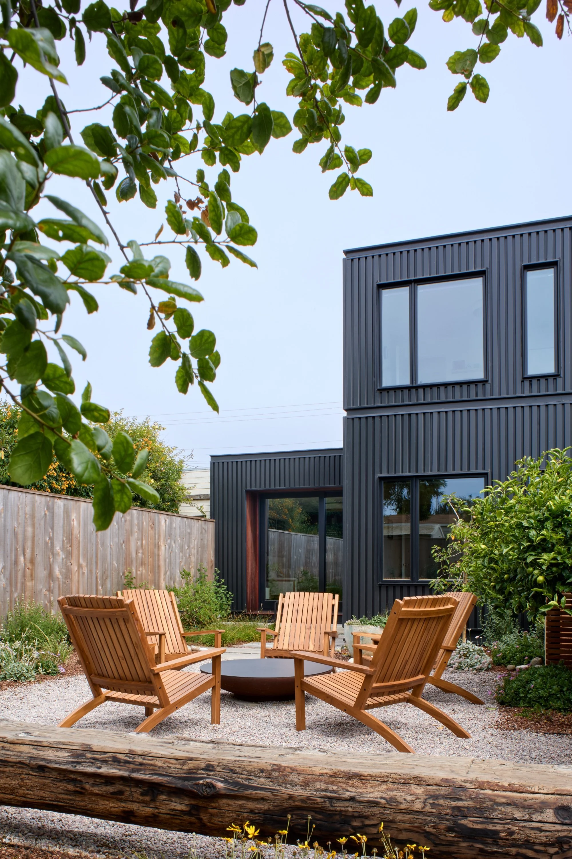 Firepit with lounge seating in front of  a modern home