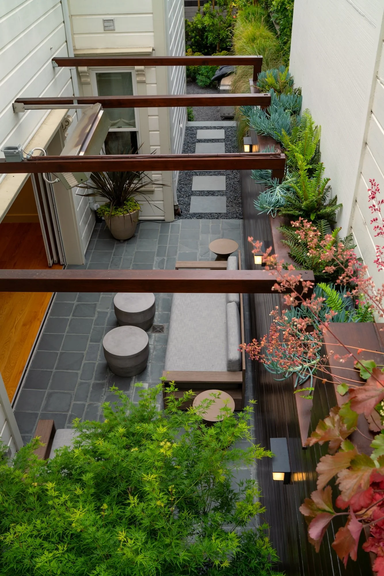 Side yard seating area with ledge plantings above in a Castro garden