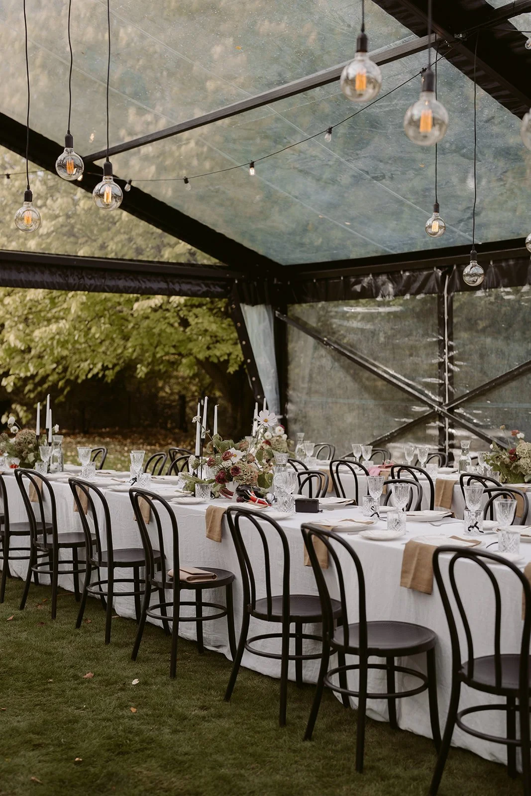 Hanging drop down lights inside a clear marquee wedding reception styled by You Gather Events.