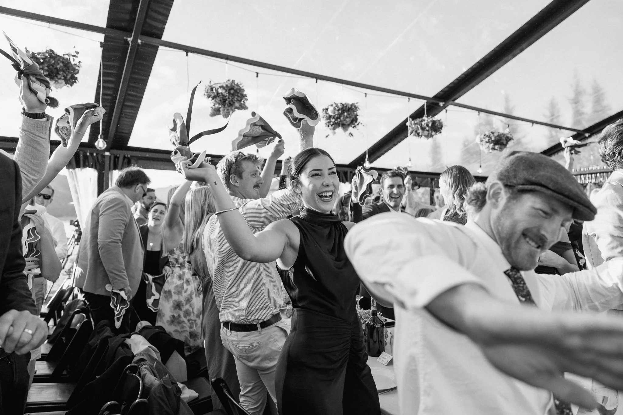Wedding guests celebrating with linen napkins inside a clear marquee by You Gather Events in Central Otago