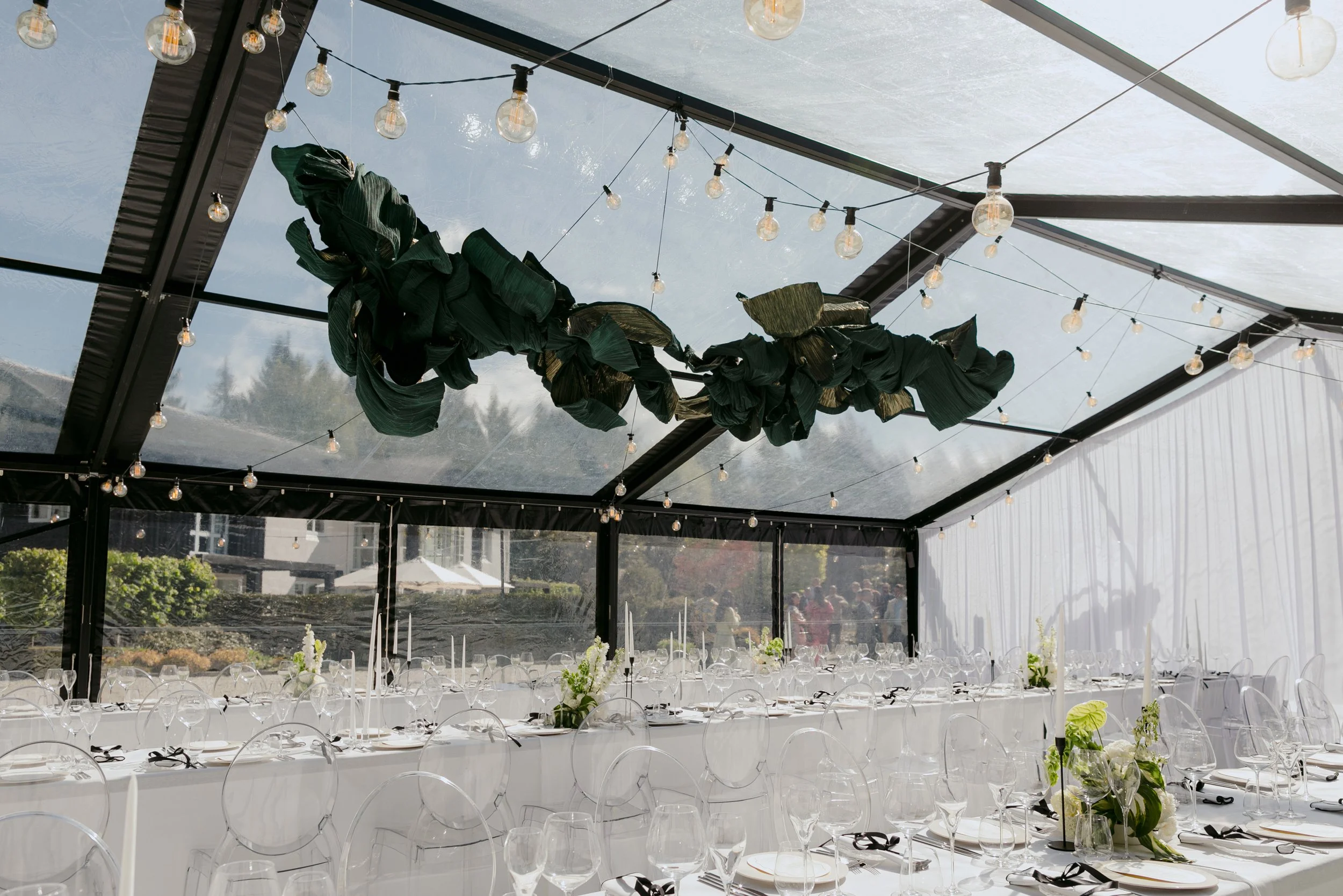Premium clear marquee wedding setup featuring white furniture and soft styling by You Gather Events