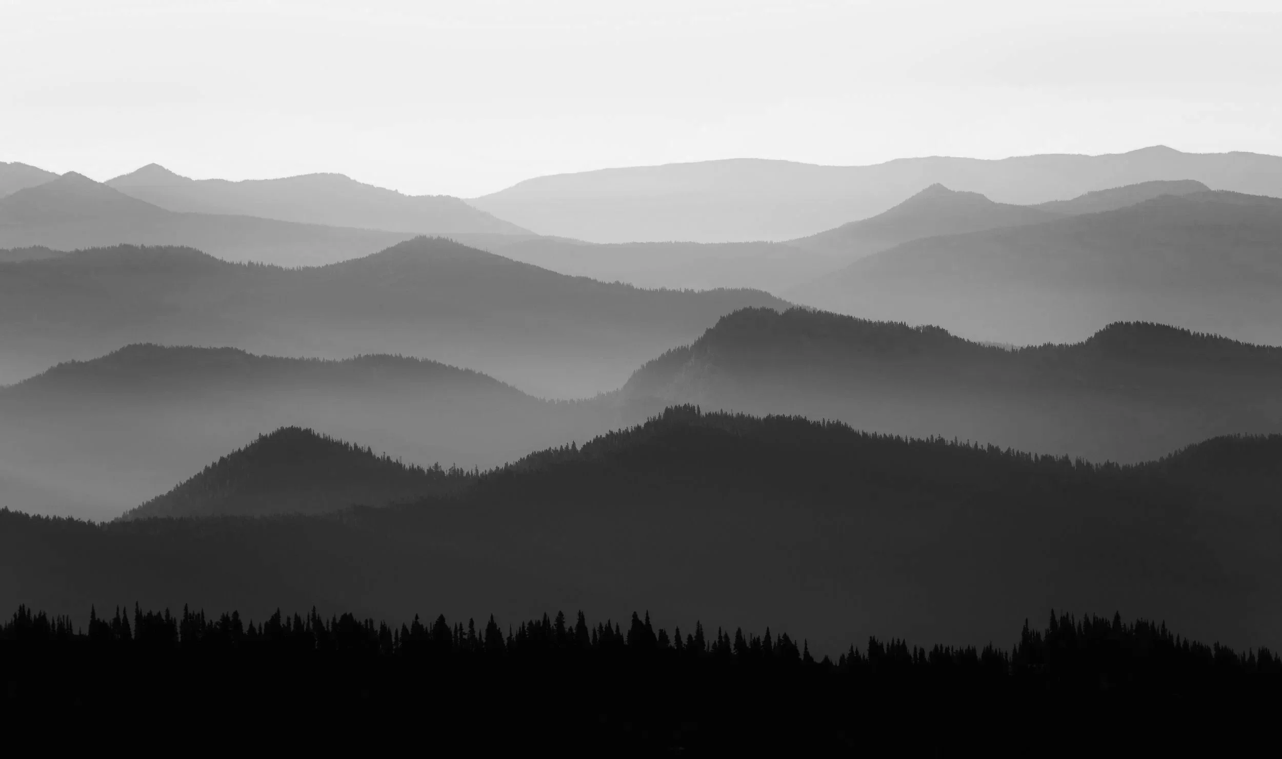 Multiple layers of blue-green mountains fading into the distance under a pale sky.