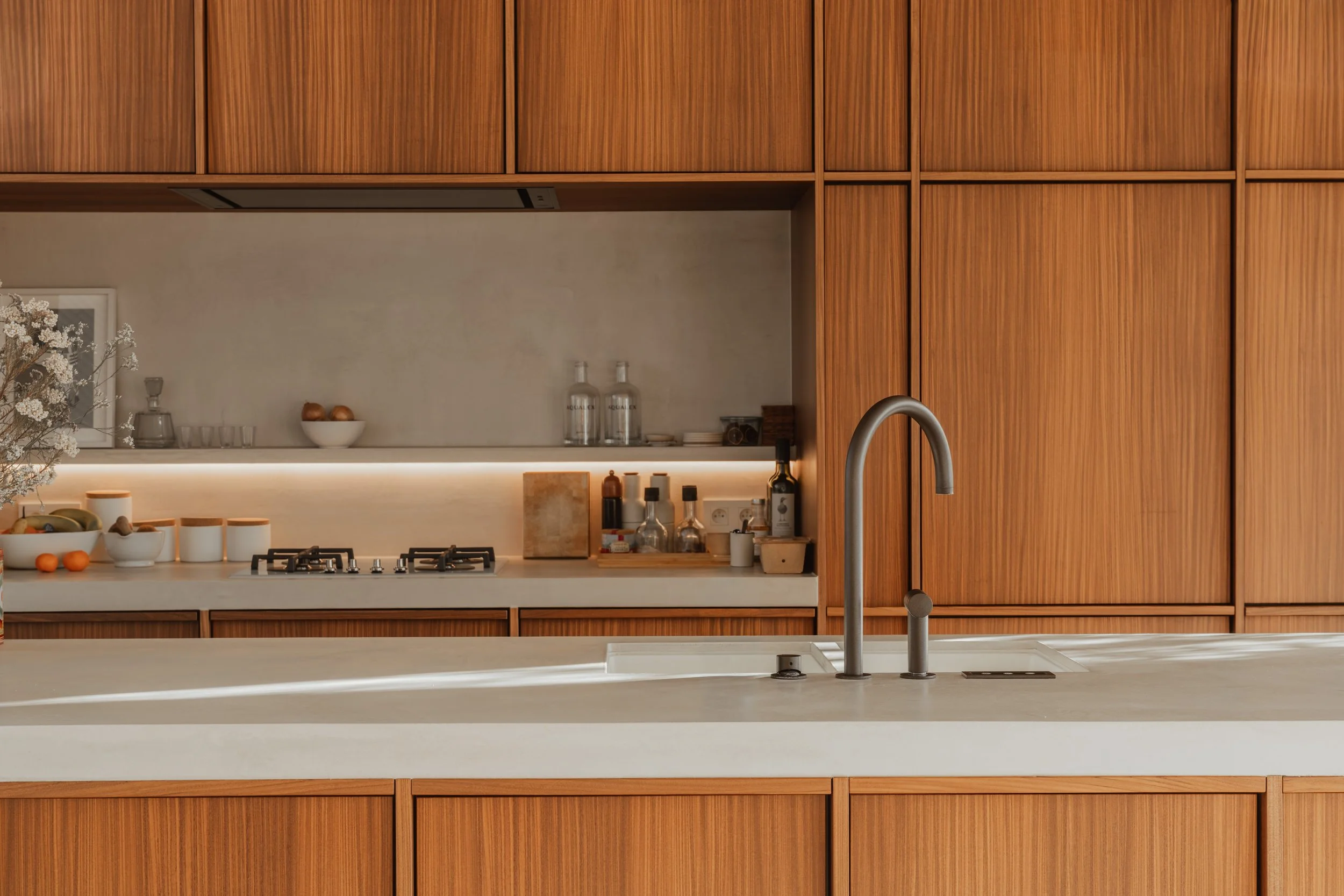 Modern kitchen with wooden cabinets, white countertop, stainless steel faucet, and built-in gas stove.