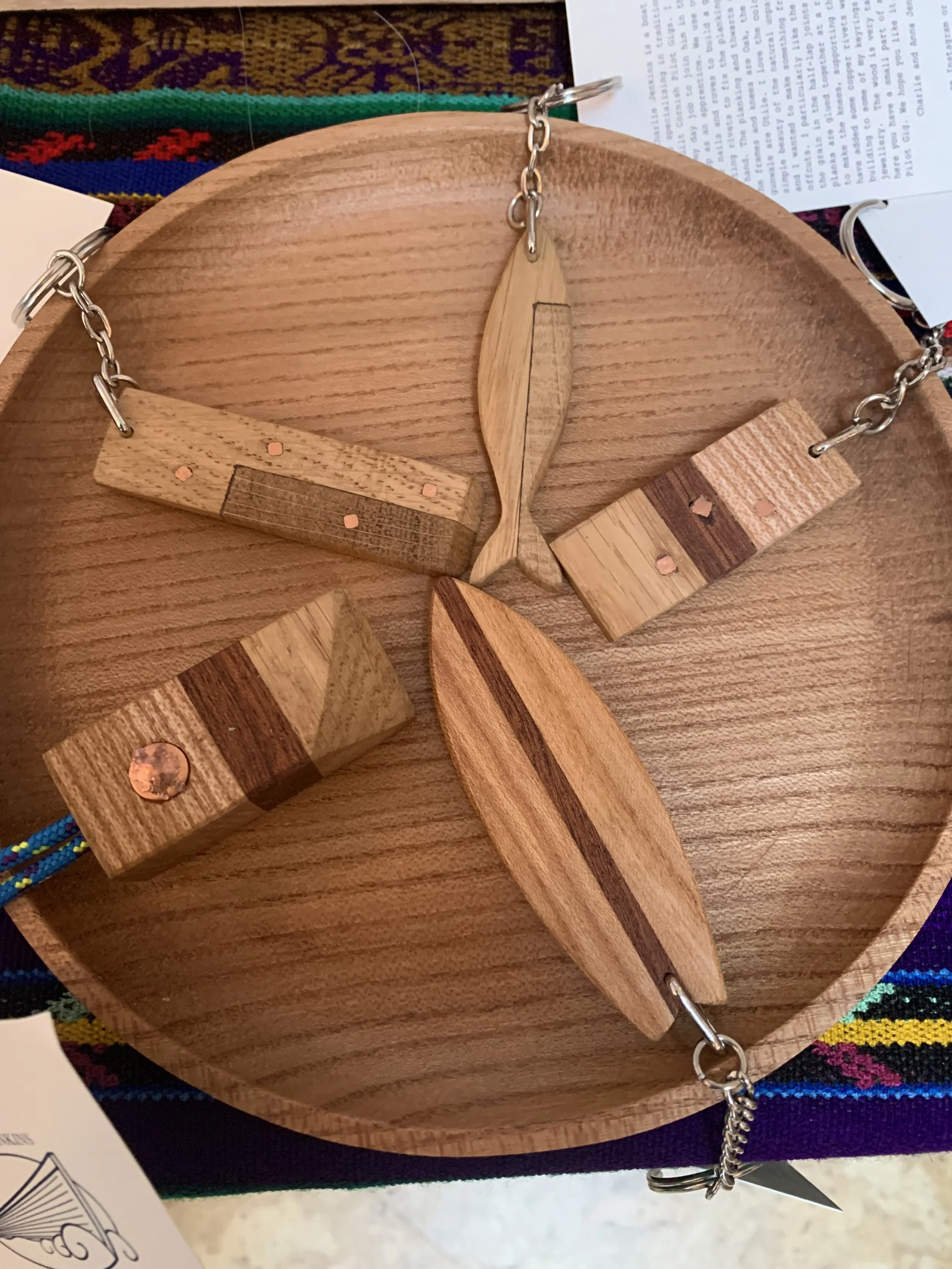 Wooden jewelry display with wooden pendant, rings, and a leaf-shaped piece on a wooden surface.