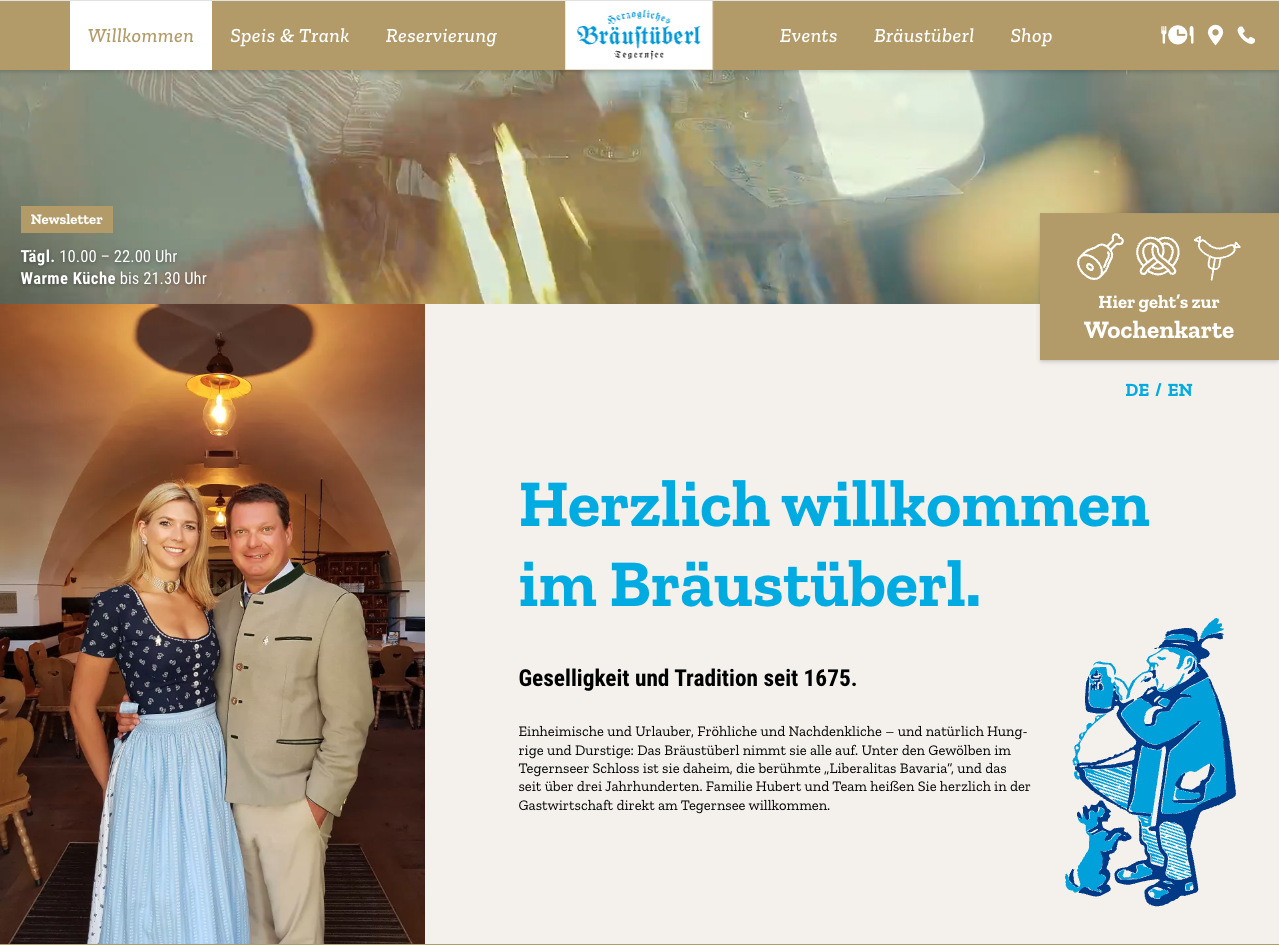Willkommensseite der Webseite des Bräustüberls Tegernsee mit einem Foto eines Paares in traditioneller bayrischer Kleidung, Text über die Gastfreundschaft und Geschichte des Ortes, Logo und Menüleiste oben.