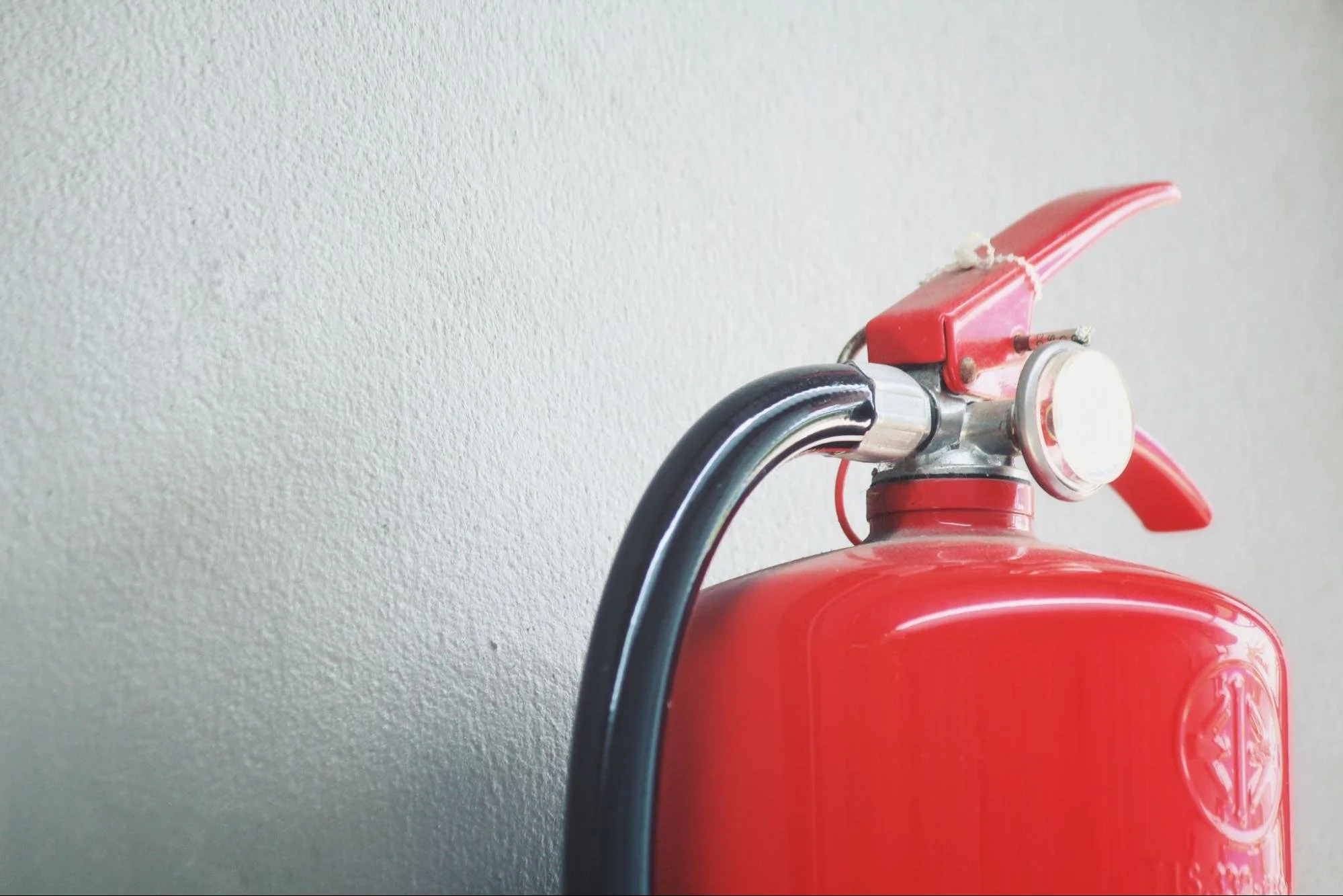 A red fire extinguisher against a gray wall.