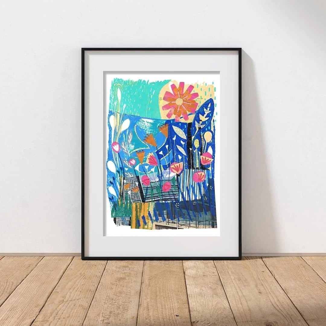 A bright and colourful mixed media collage print showing flowers and a coastal scene - framed and mounted.