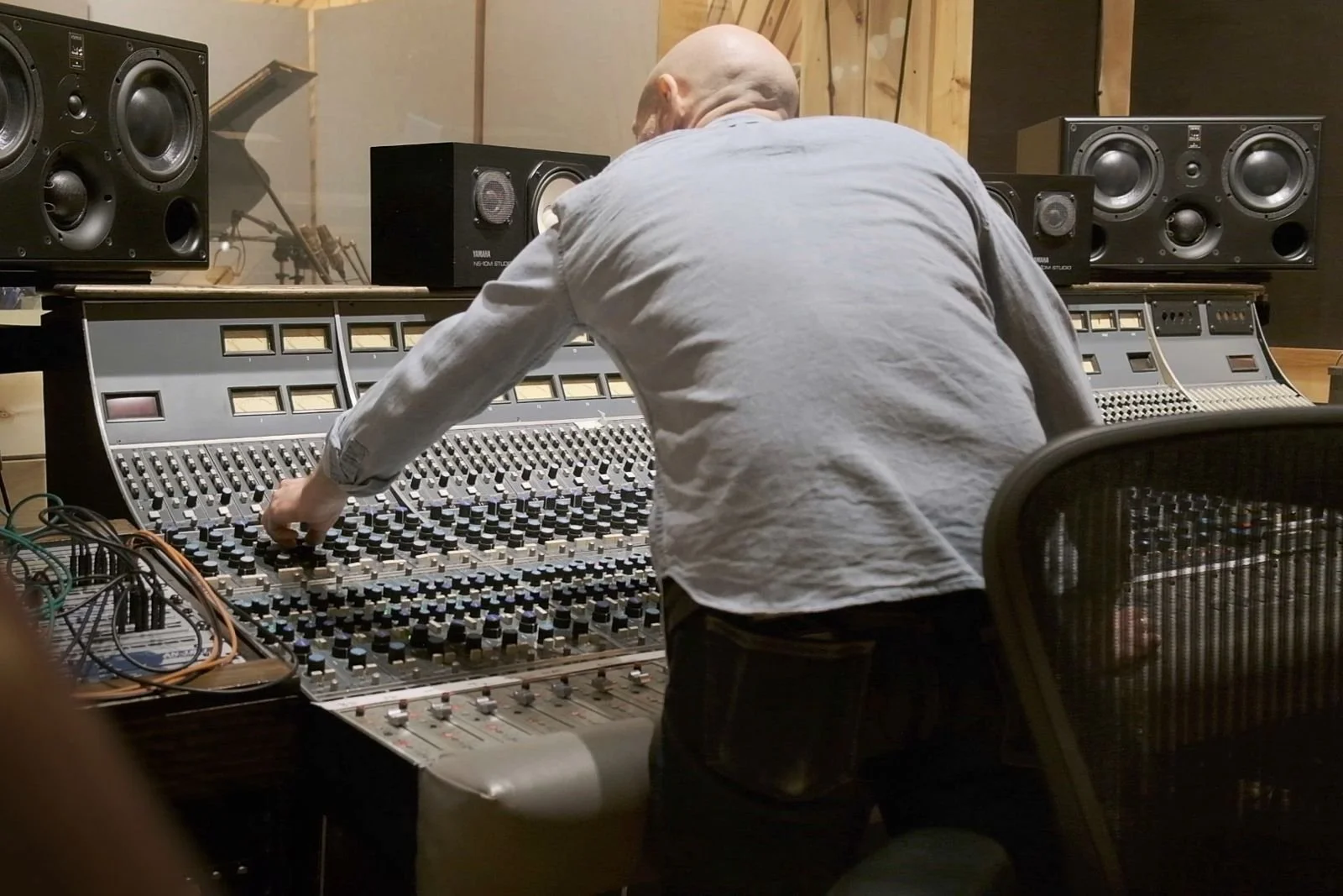 Person adjusting mixing console in recording studio with speakers