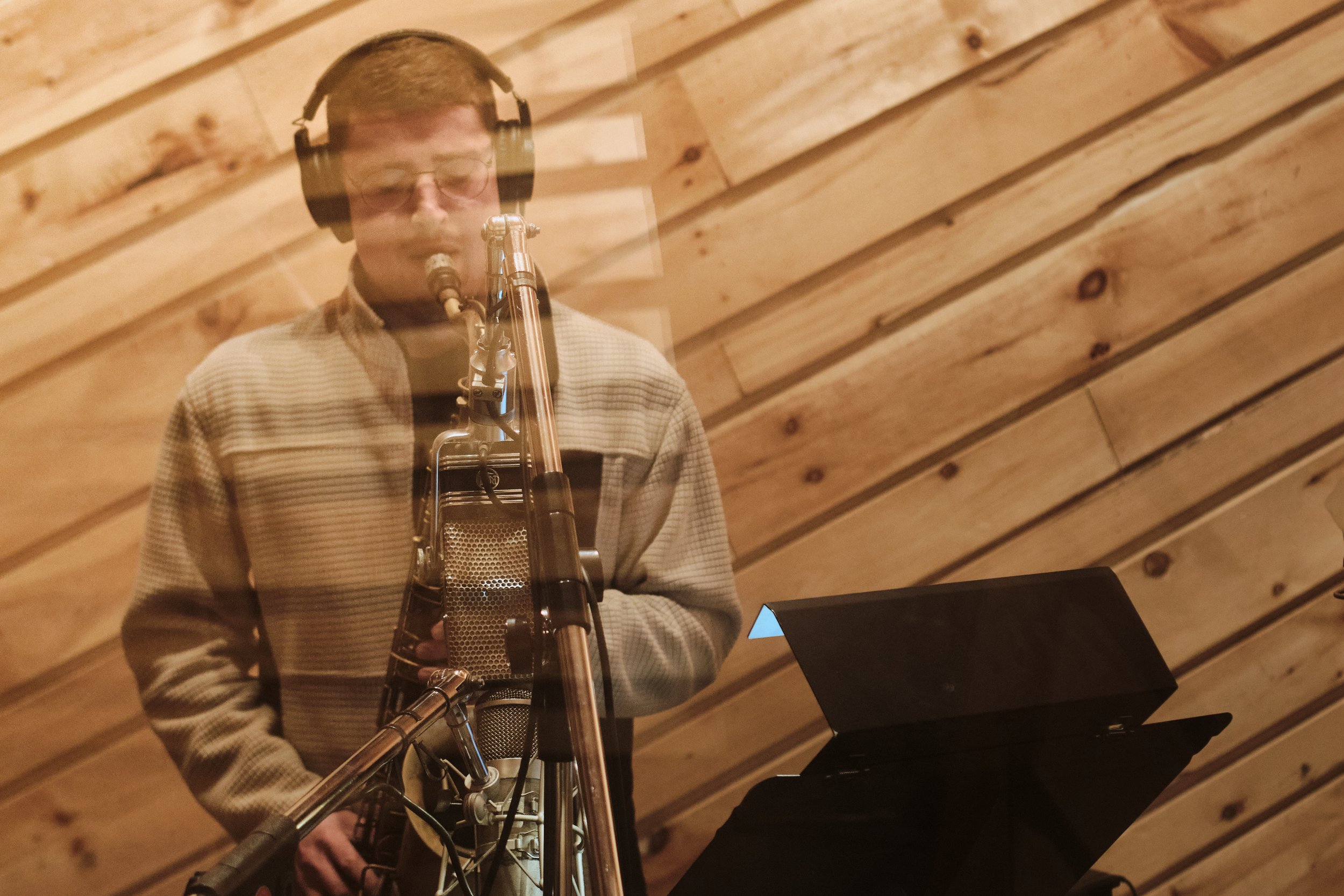 Alain Metrailler playing saxophone in recording studio with headphones