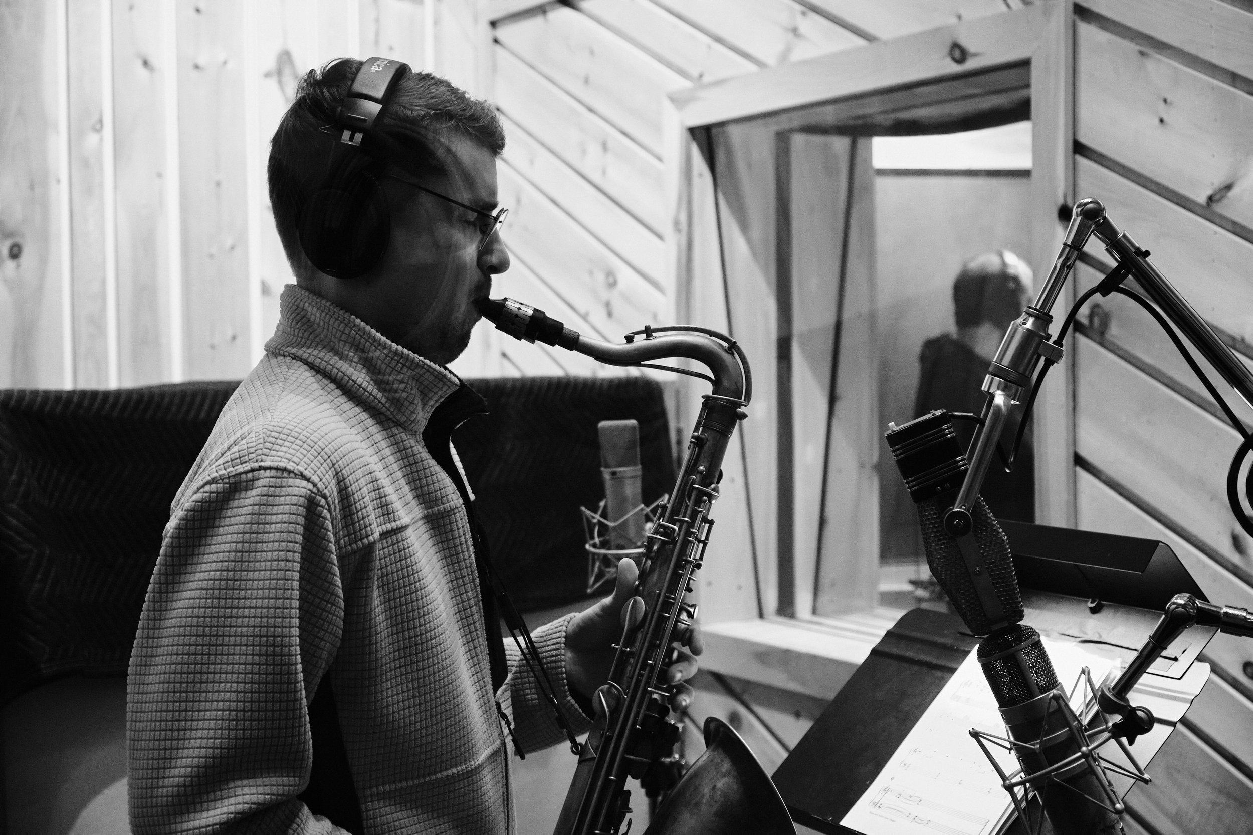 Musician playing saxophone in recording studio with headphones