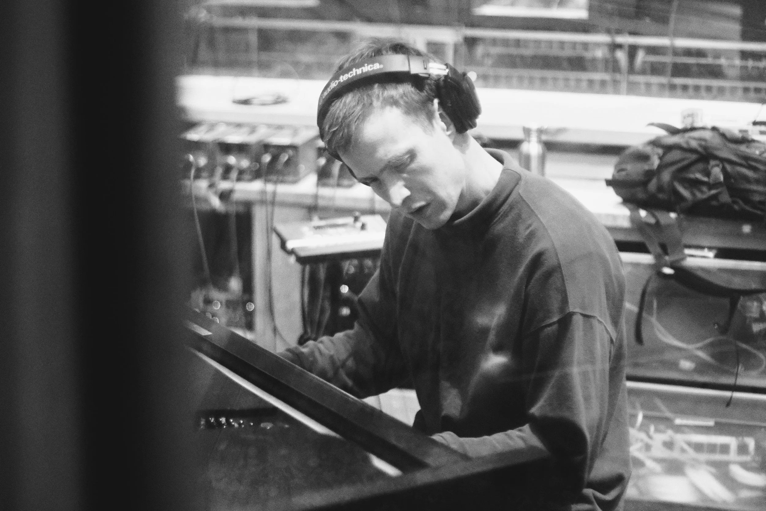 Person wearing headphones playing a piano in a studio setting.