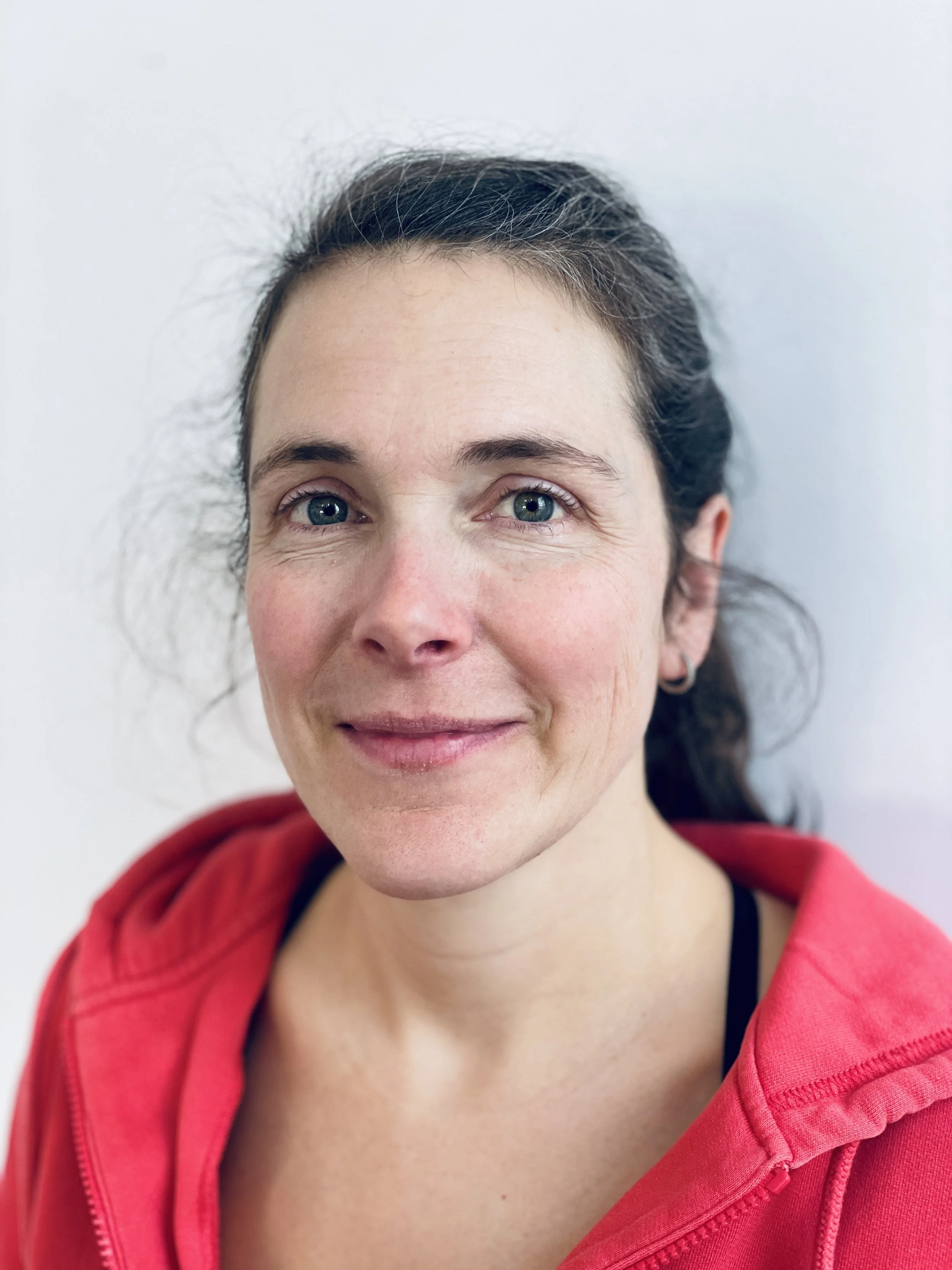 Femme souriante portant un sweat à capuche rouge, vue de près.