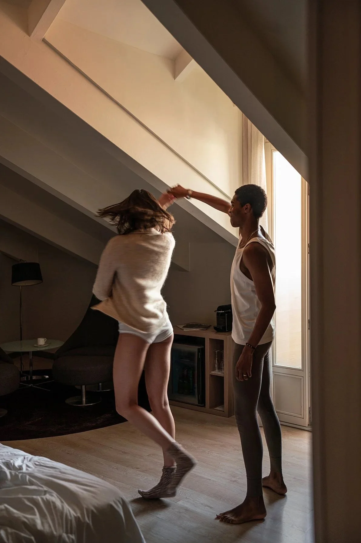 Atmospheric luxury hospitality photography capturing a couple dancing inside a hotel room through cinematic light and emotional intimacy.
