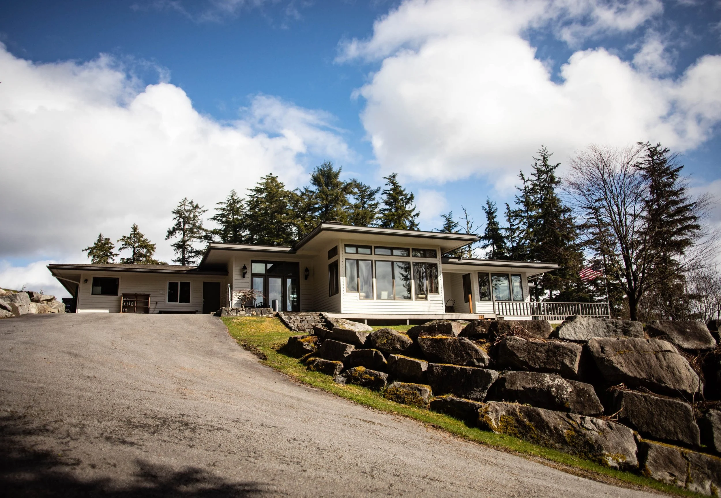Chrome Chasers fishing lodge exterior in Wrangell Alaska showing the Frank Lloyd Wright-inspired architecture built above a moss-covered bedrock outcropping on the hillside above town