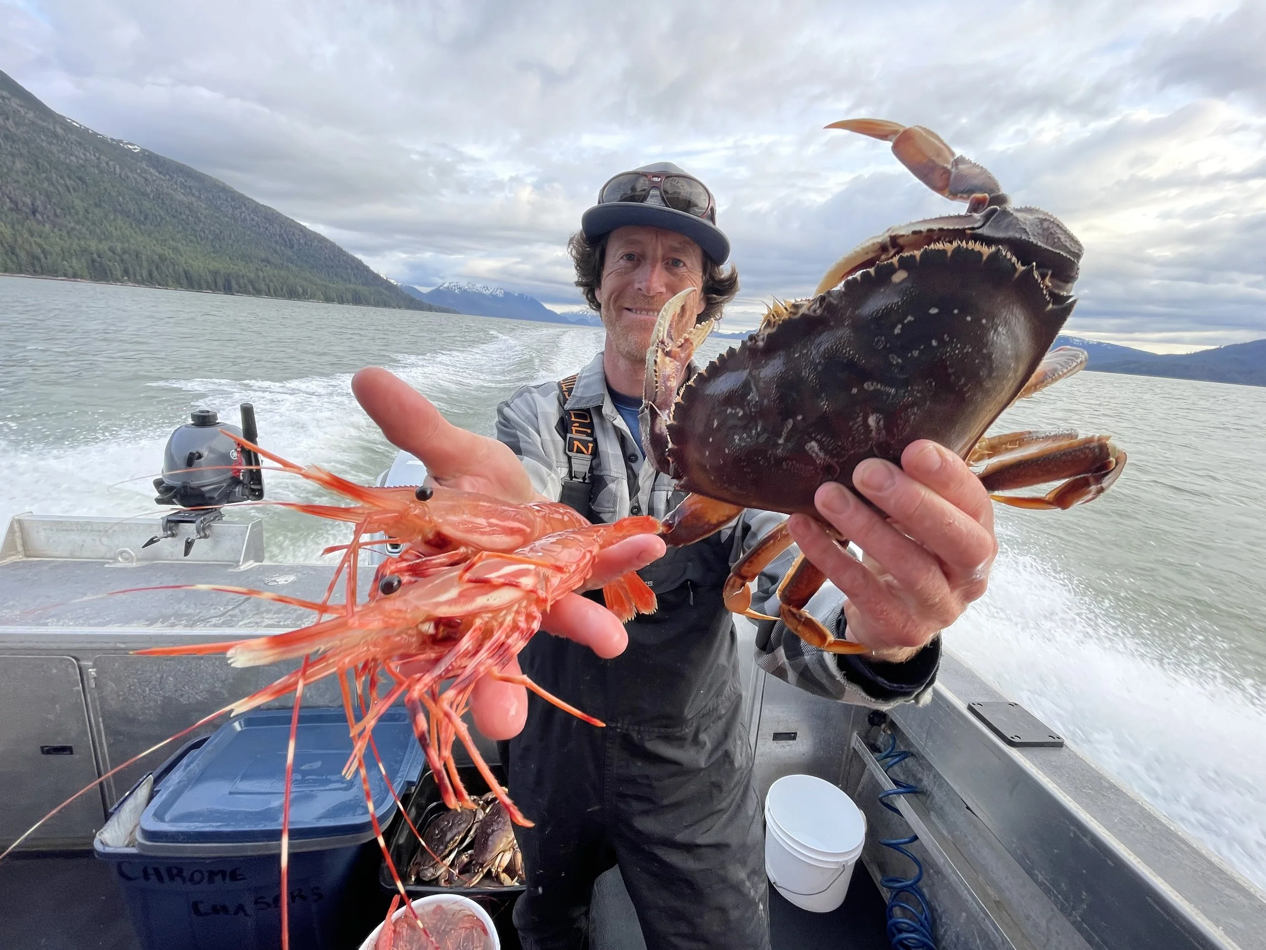 Guest holding Dungeness crab and spot prawns on the Chromagnum in Wrangell, Alaska