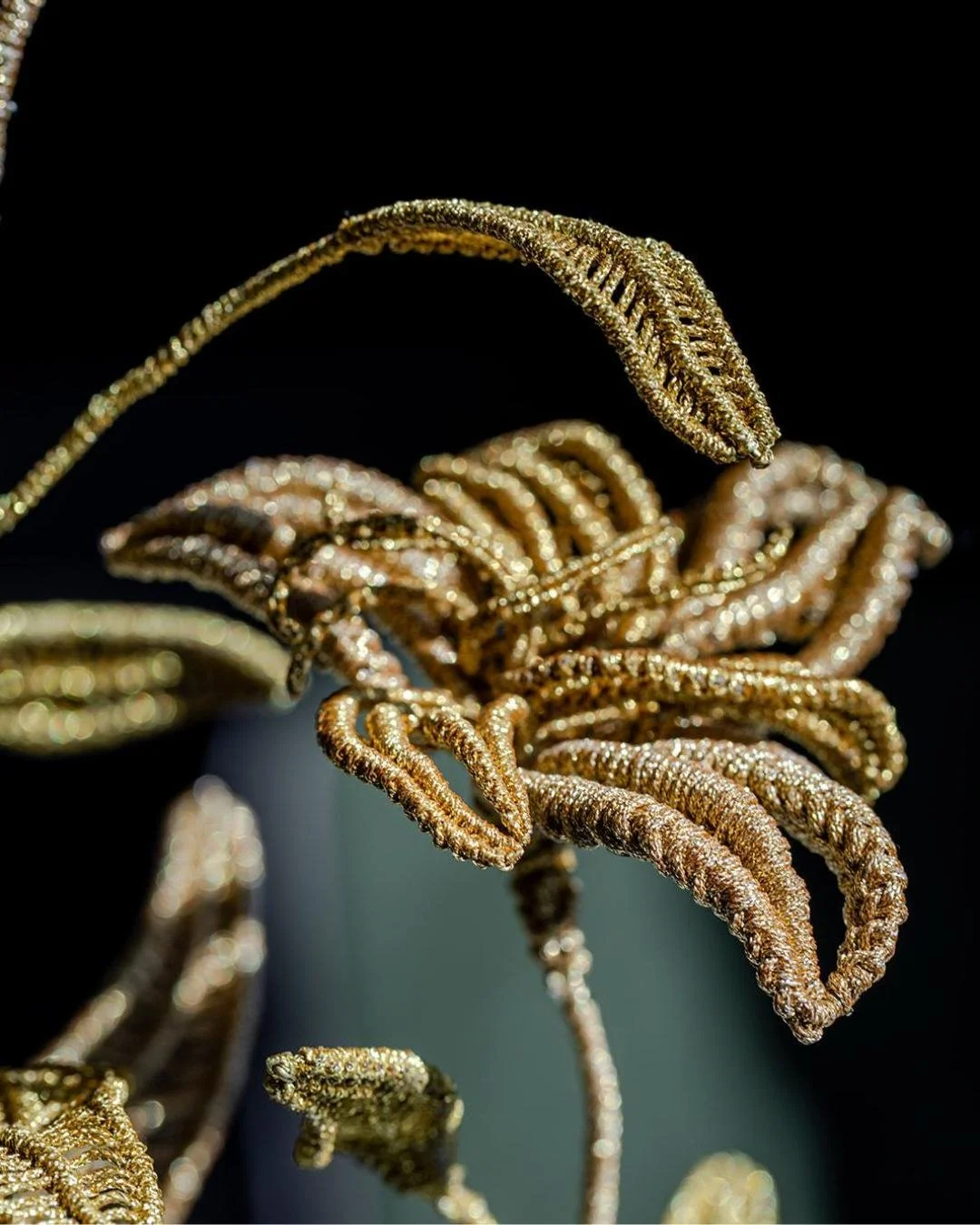 Les Lys

From the weight of blown glass, something impossibly delicate begins to grow.

Golden lilies emerge from the glass in fine thread, their stems, leaves and petals shaped with an extraordinary intricacy. There is a beautiful tension between th