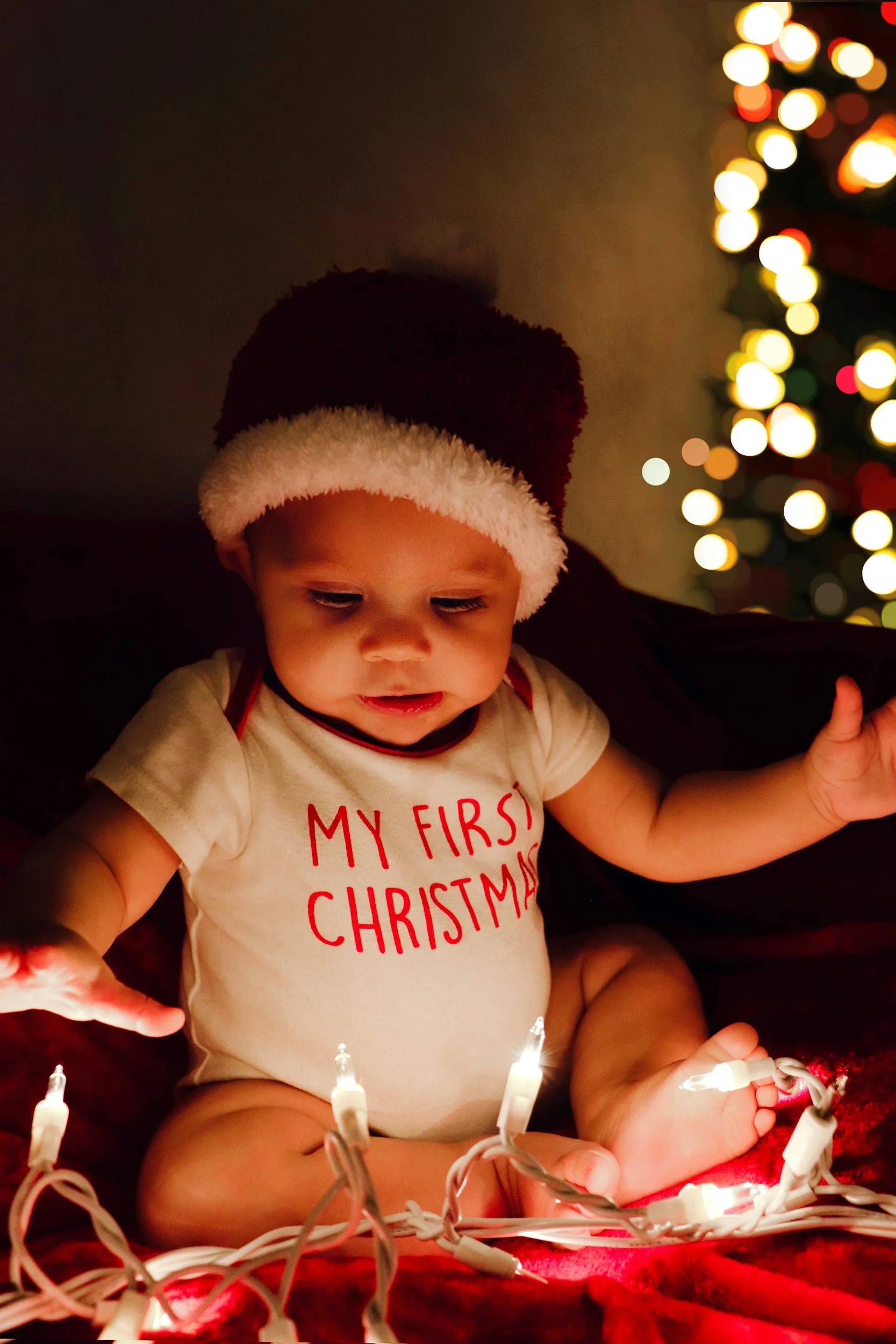 baby under christmas tree wearing "my first christmas" onesie