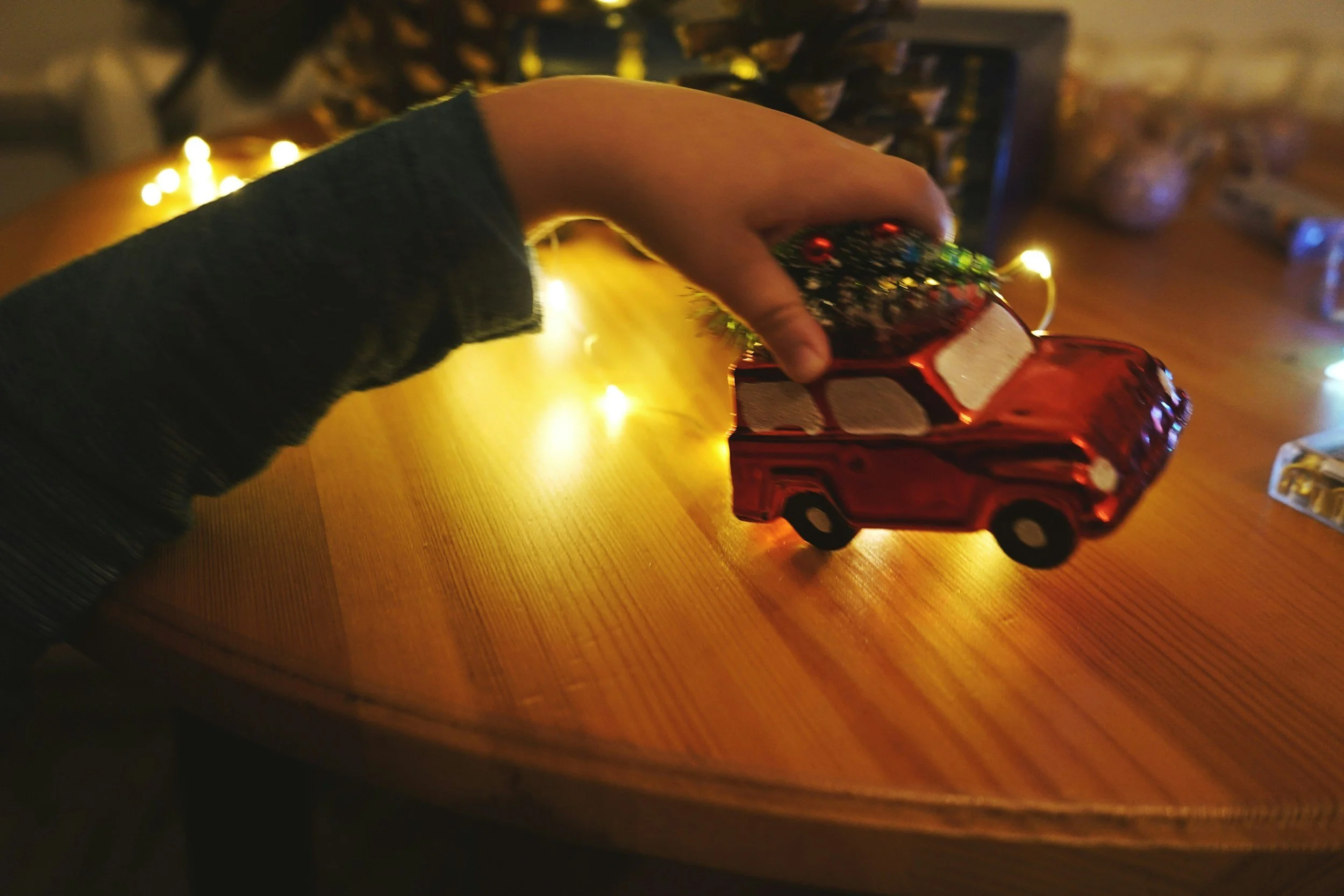 older kid playing with toy car in front of christmas tree
