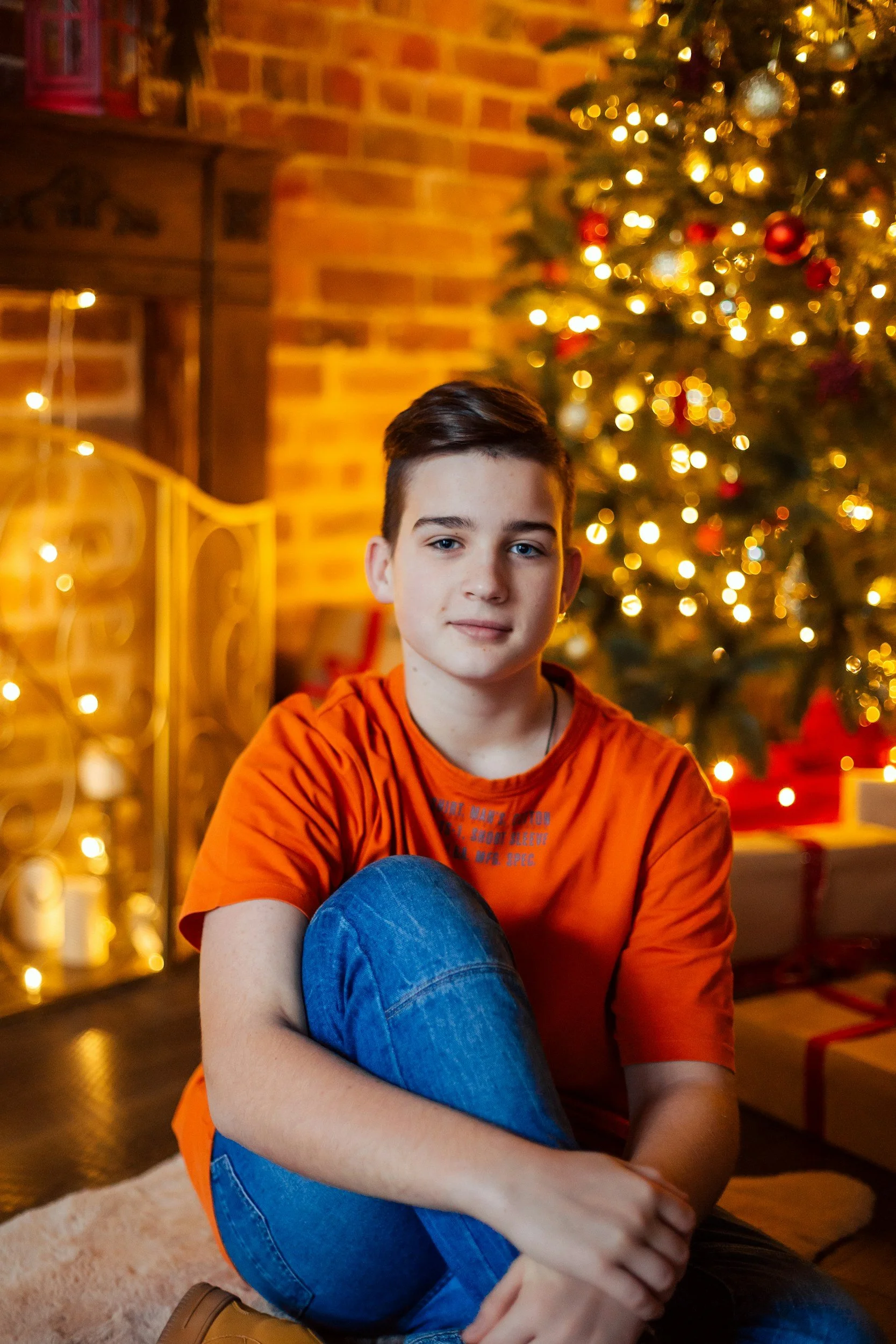 Teen sitting in front of Christmas tree