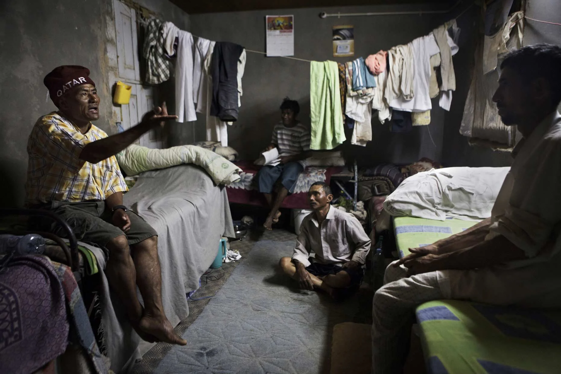 QATAR. 2012. Two hours drive outside of Doha, guest workers man a vegetable growing farm, irrigated by groundwater. Laborers resting in the evening, in the small concrete shed where they live.