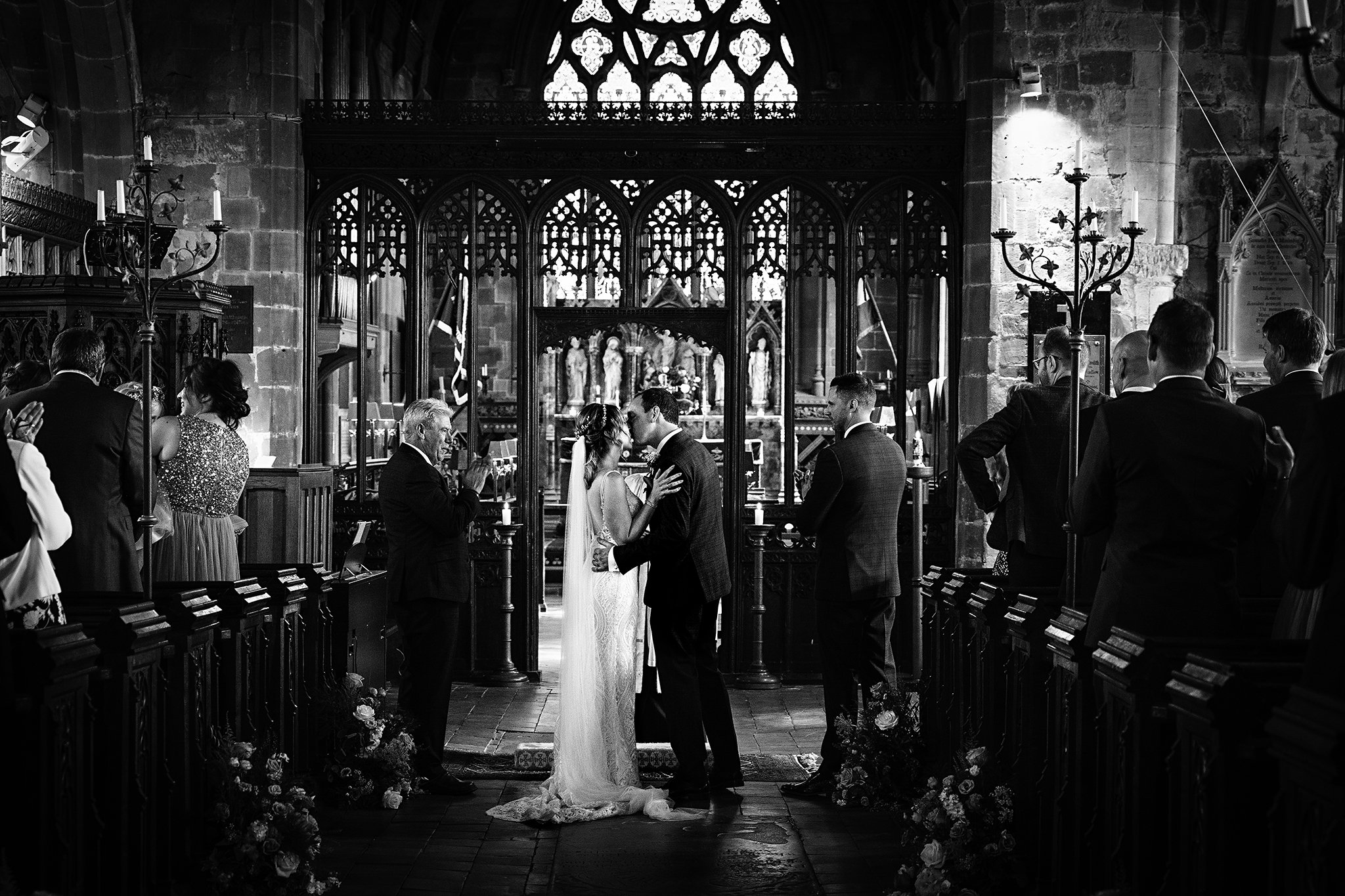  Black and white photo of the first kiss at a wedding in a church in Worfield, Shropshire 
