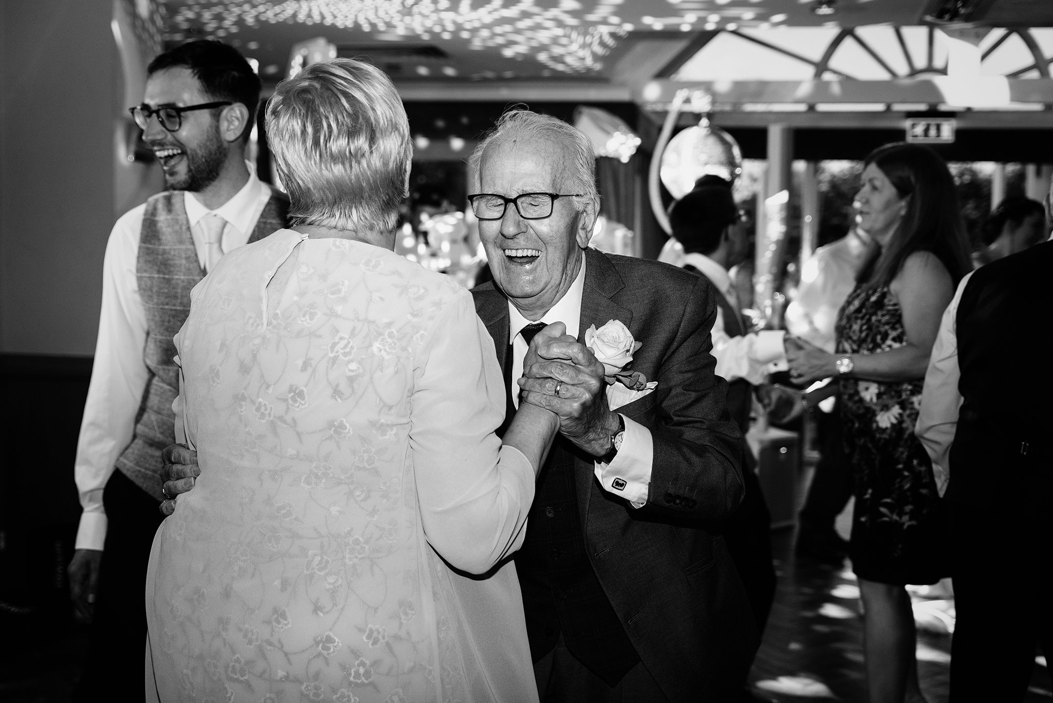  A black and white photo of the groom’s grandfather dancing at a wedding reception 