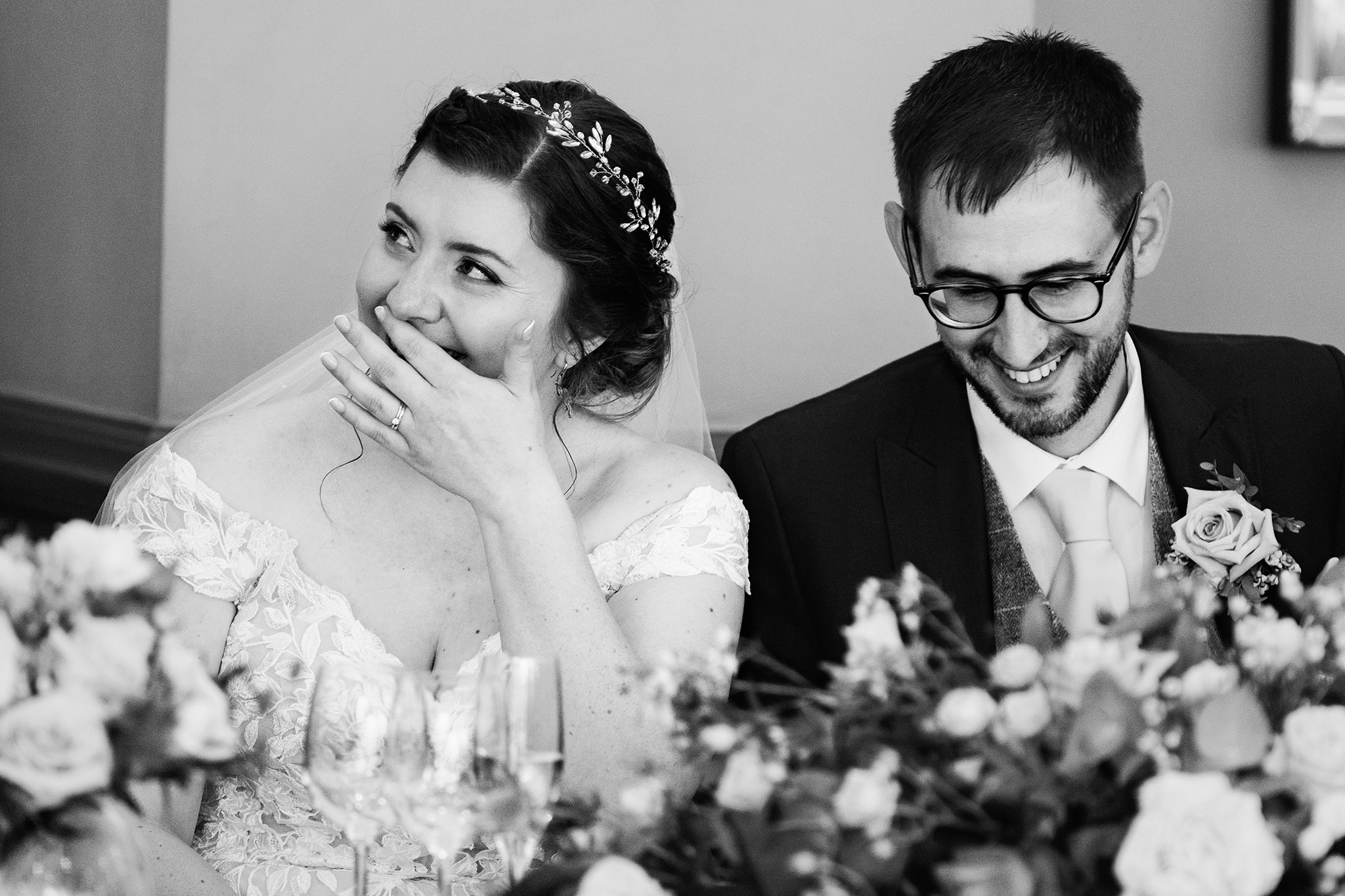  Photo of a bride and groom laughing during wedding reception speeches 