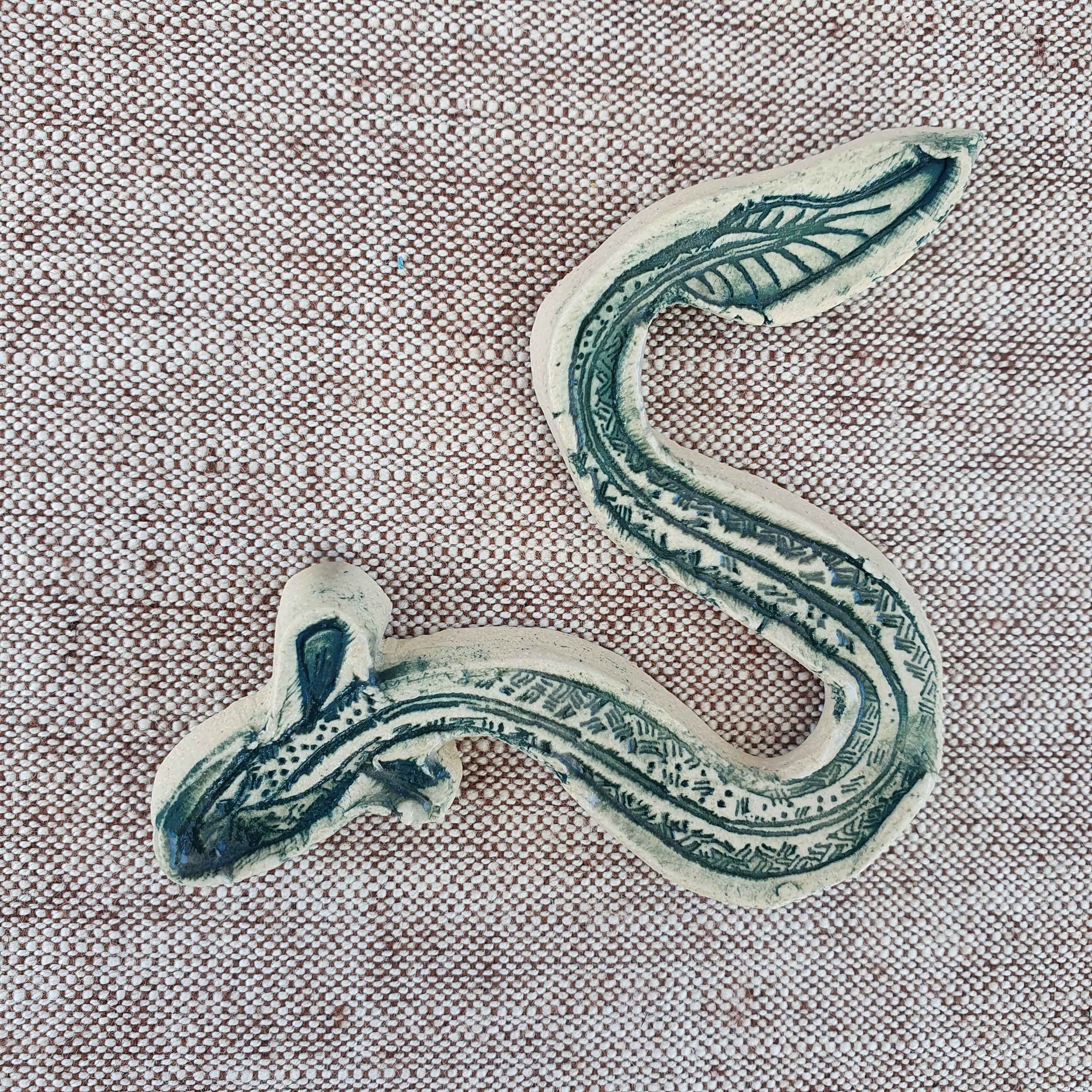 Ceramic eel glazed in green lay on a linen table cloth.