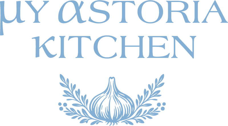 Logo for buy astoria kitchen with a garlic bulb and decorative olive branches below the text in blue.