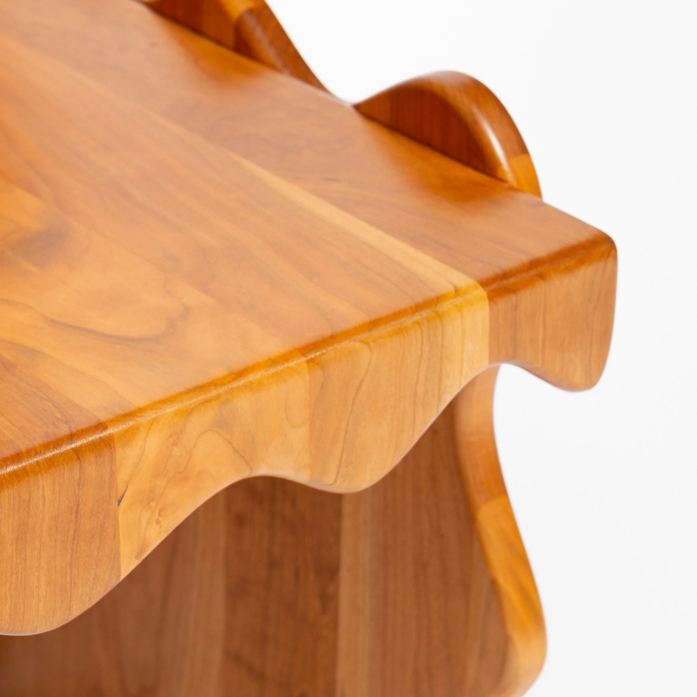 Close-up of a wooden furniture piece with detailed carved edge and smooth polished surface.