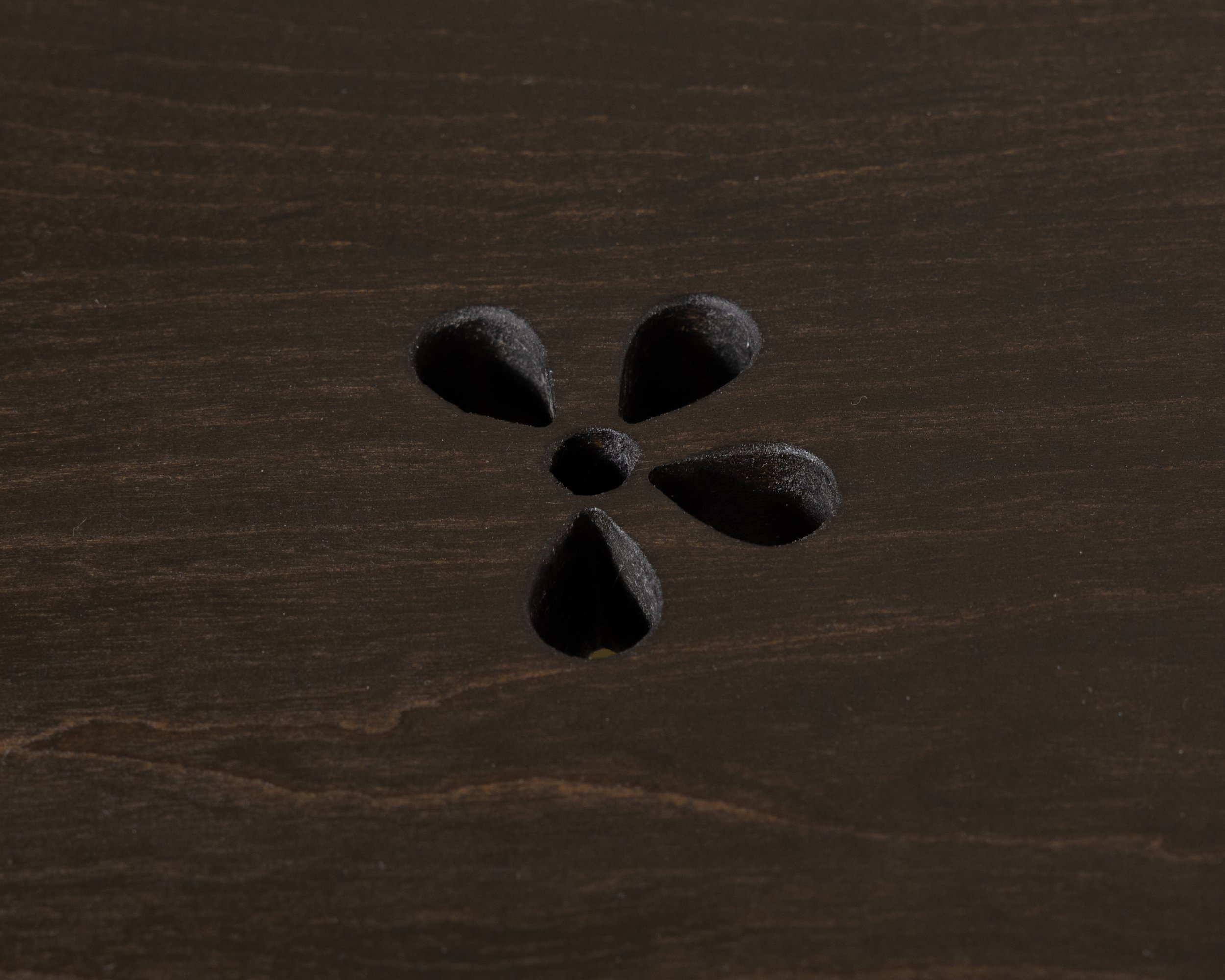 Black heart-shaped stones and round stones on a dark wooden surface.