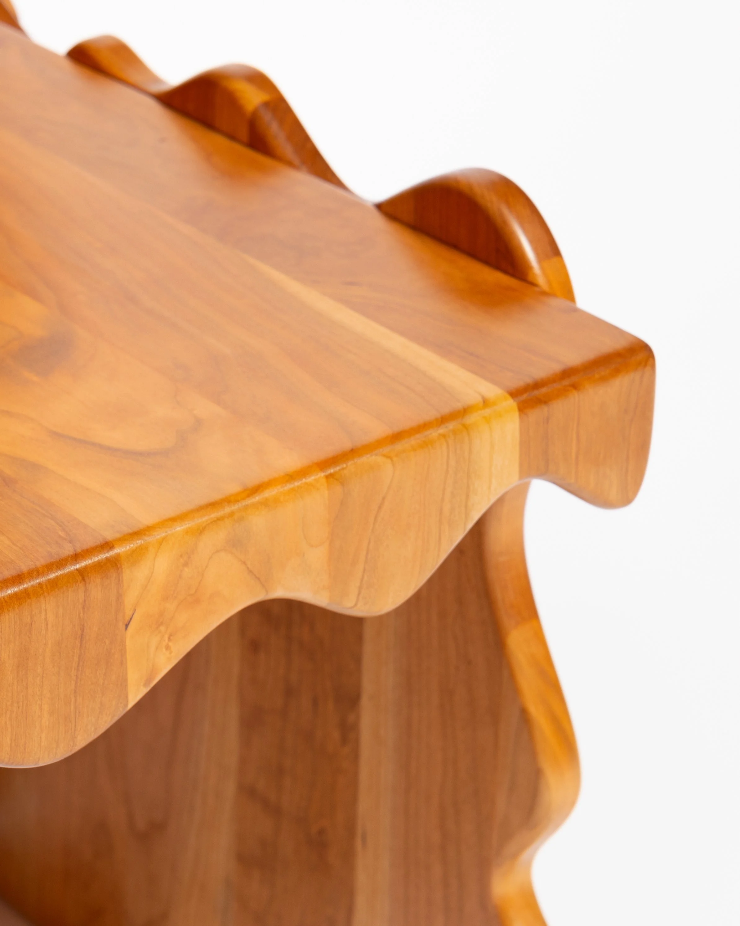 Close-up image of a wooden piece of furniture with curved decorative edges and smooth finish.