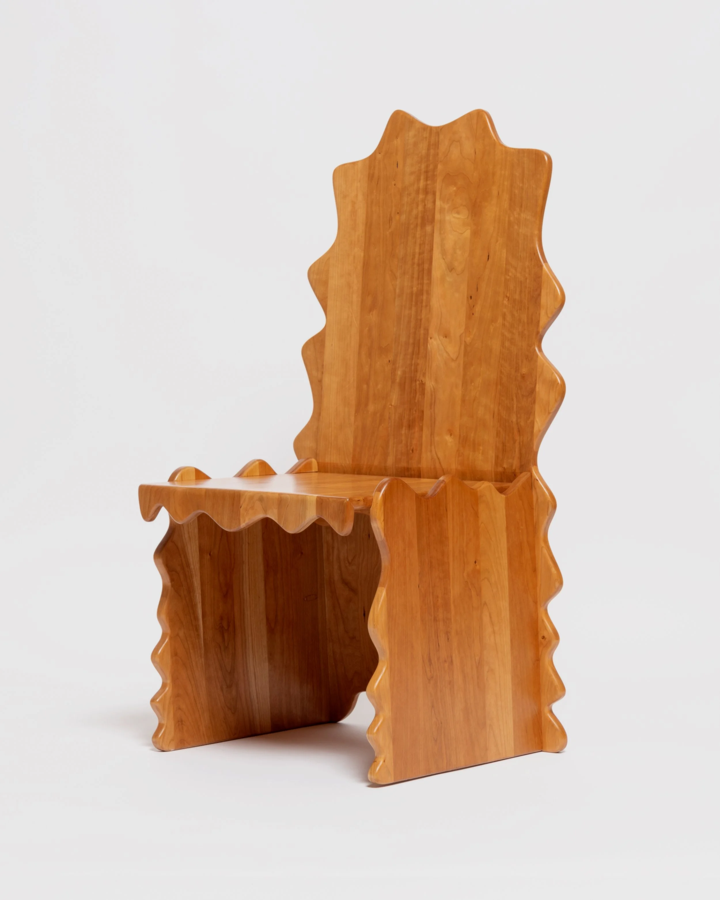 A wooden chair with a high back and decorative edge details, set against a plain white background.