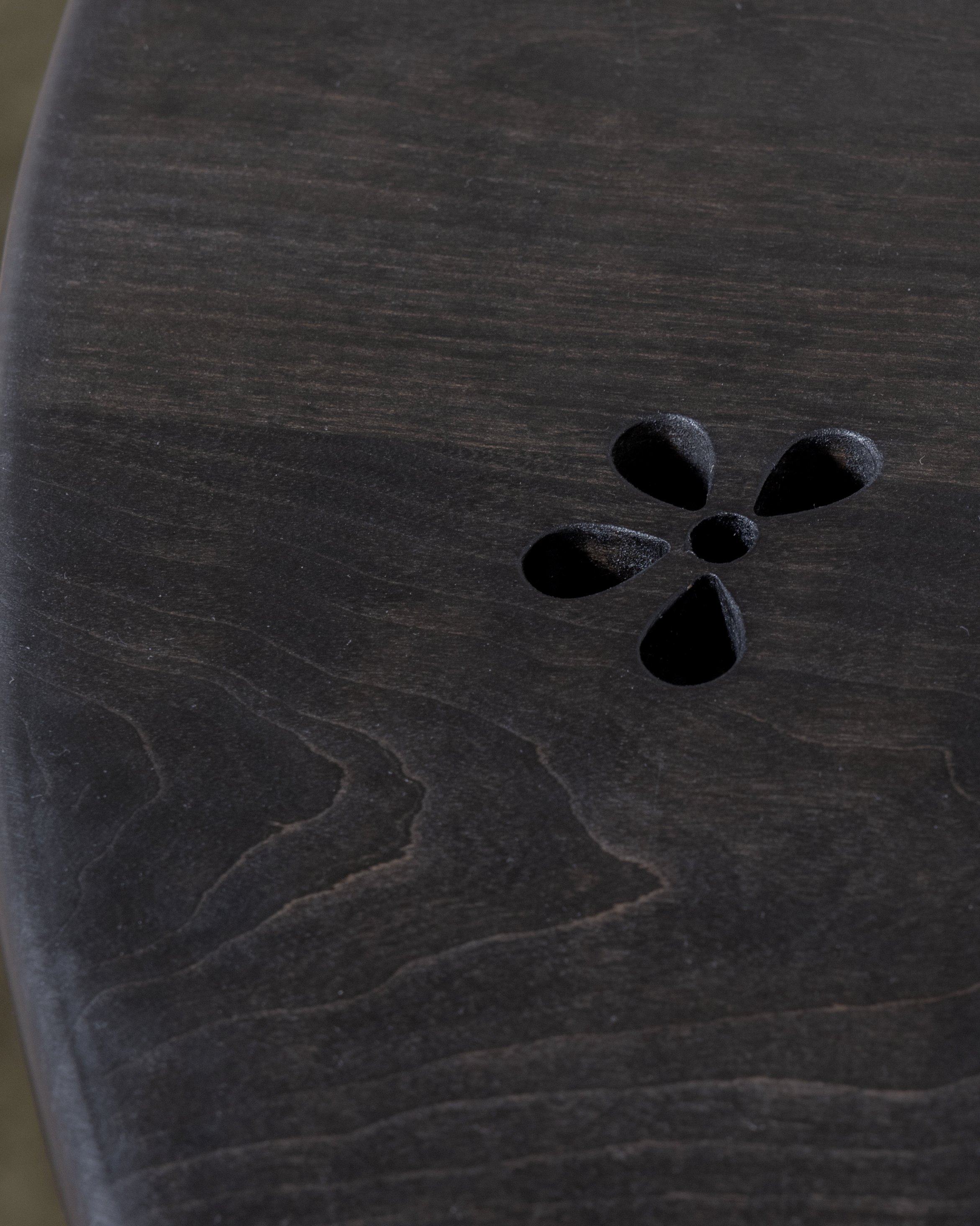 A dark-colored wooden surface with a flower-shaped carved design in the lower right corner.