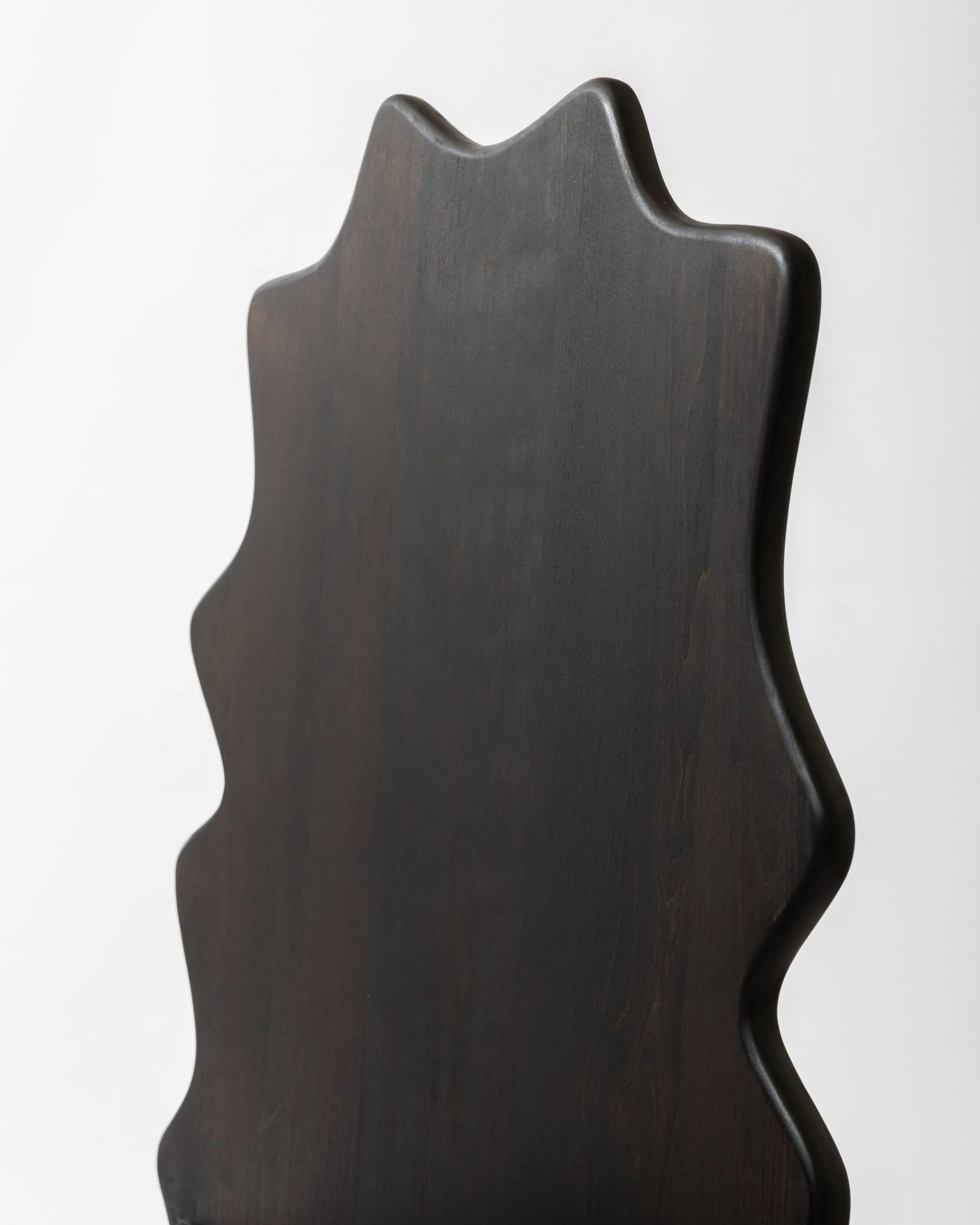 Close-up of a dark wooden chair with a curved backrest against a plain white background.