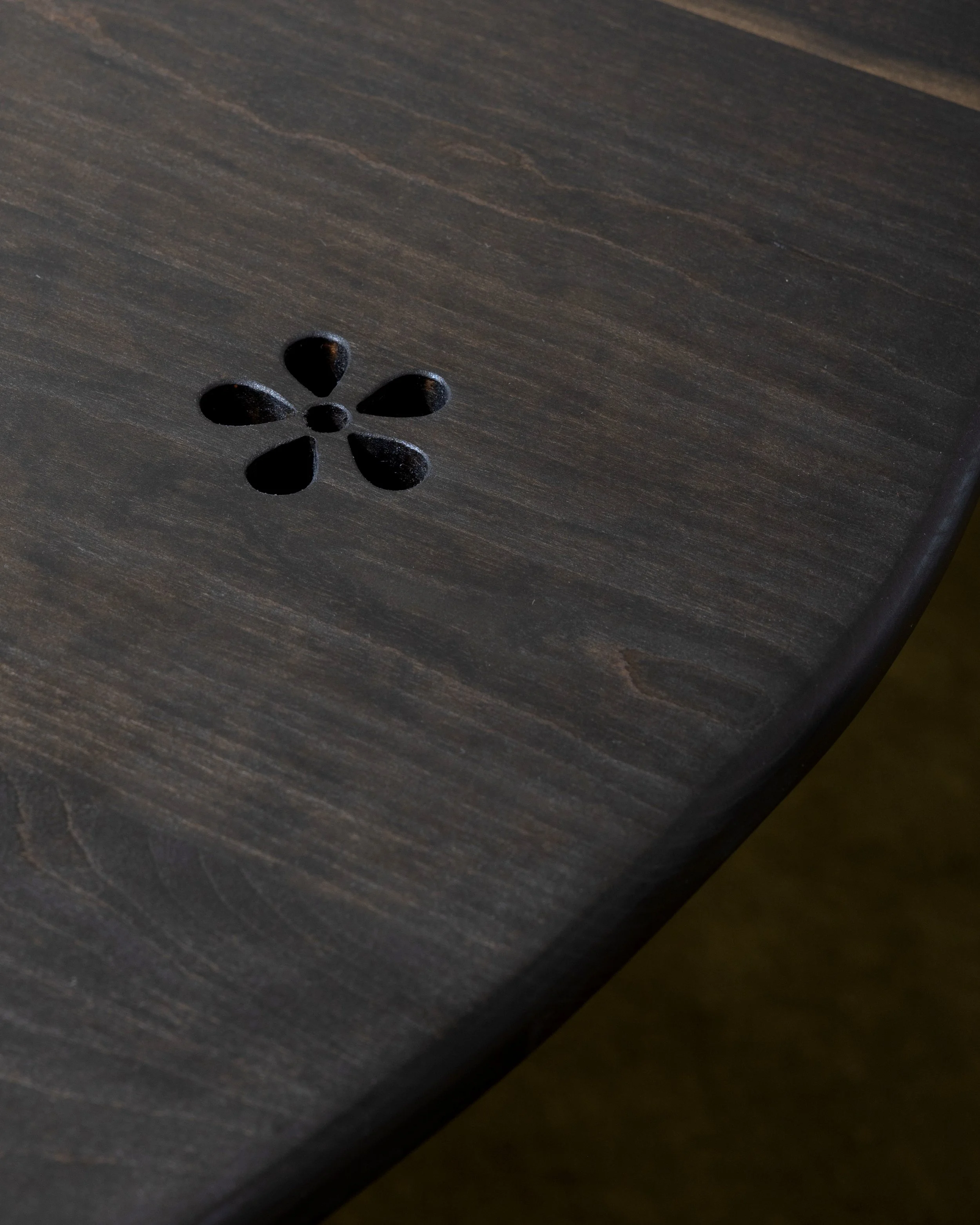 Close-up of a dark wooden surface with a flower-shaped hole pattern.