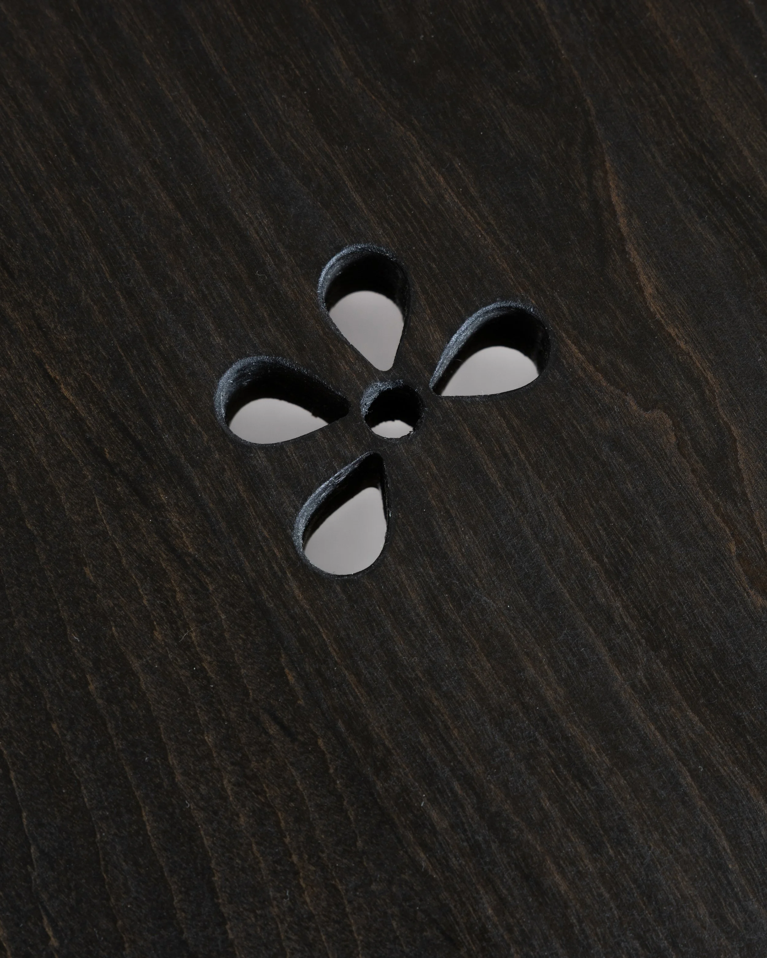 Close-up of a dark wooden surface with a decorative floral cutout.