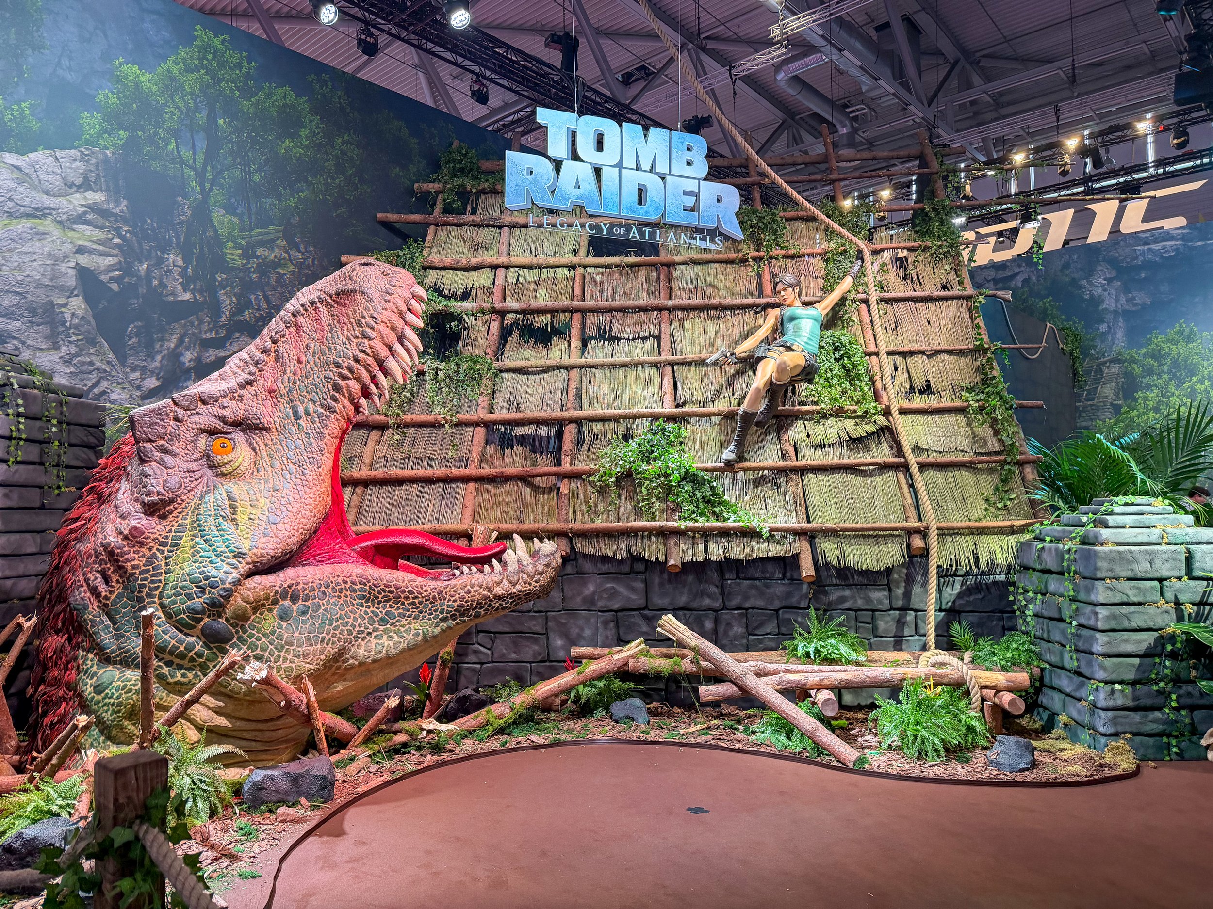 Tomb Raider: Legacy of Atlantis experience at Gamescom 2026 featuring a large T Rex, Lara Croft and immersive jungle scenery.