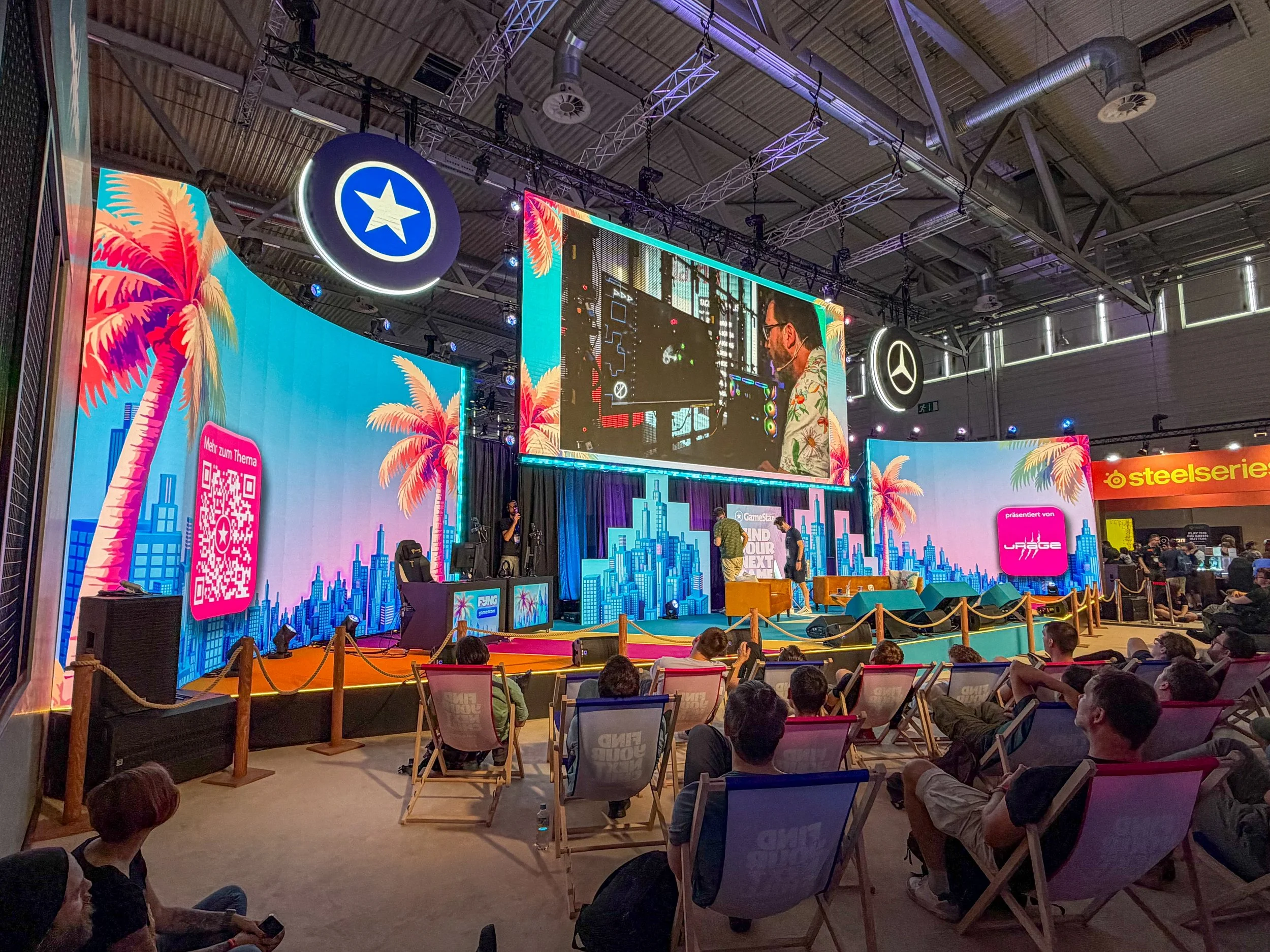 Live gaming stage at Gamescom 2026 with visitors seated in front of a large screen during an on stage presentation