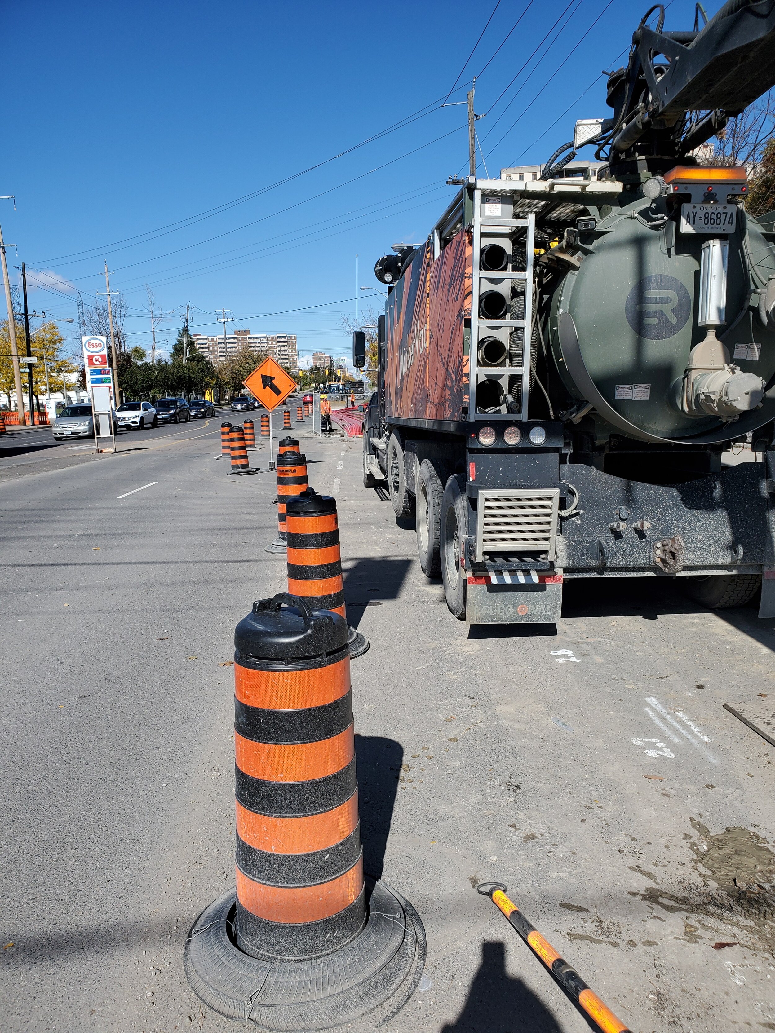 Street with construction cones, a road work sign, and a large industrial truck